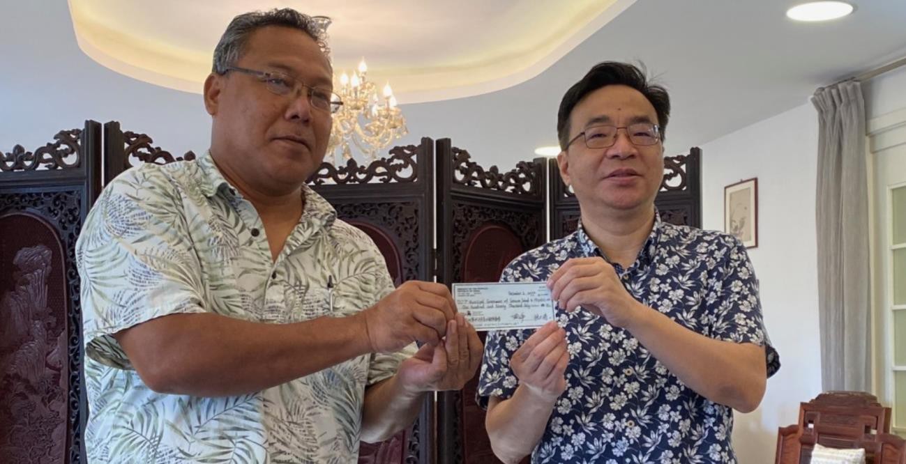Alfred Ansin and Huang Zheng pose with the check for $190,000.