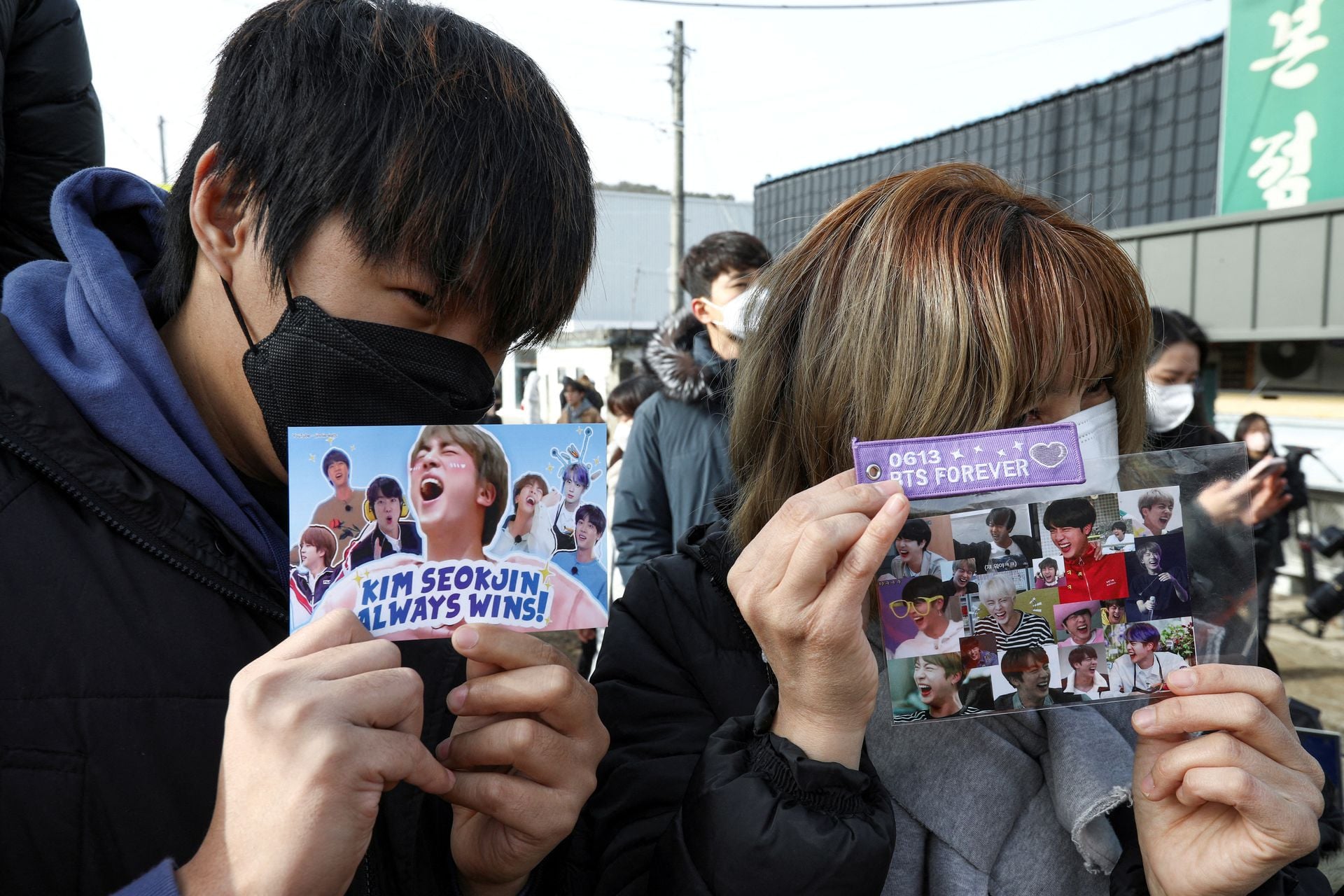 Fans hold up cards with pictures on it as they wait for the arrival of Jin, the oldest member of the K-pop band BTS, outside a South Korean army boot camp near the demilitarized zone separating the two Koreas, in Yeoncheon, South Korea on Dec. 13, 2022.