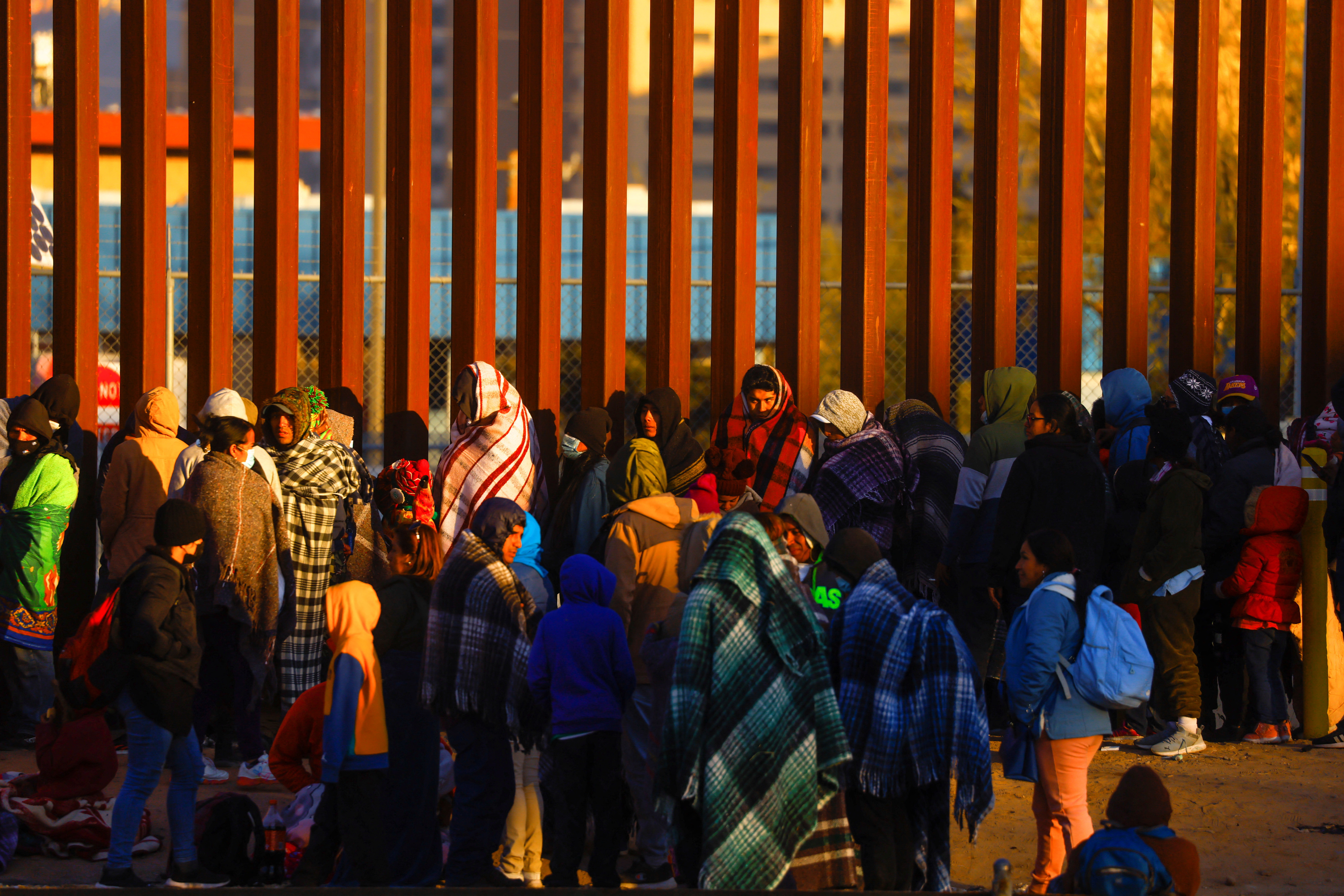 Migrants queue near the border fence, after crossing the Rio Bravo river, to turn themselves in to U.S. Border Patrol agents and request asylum in El Paso, Texas as seen from Ciudad Juarez, Mexico, Dec. 21, 2022.