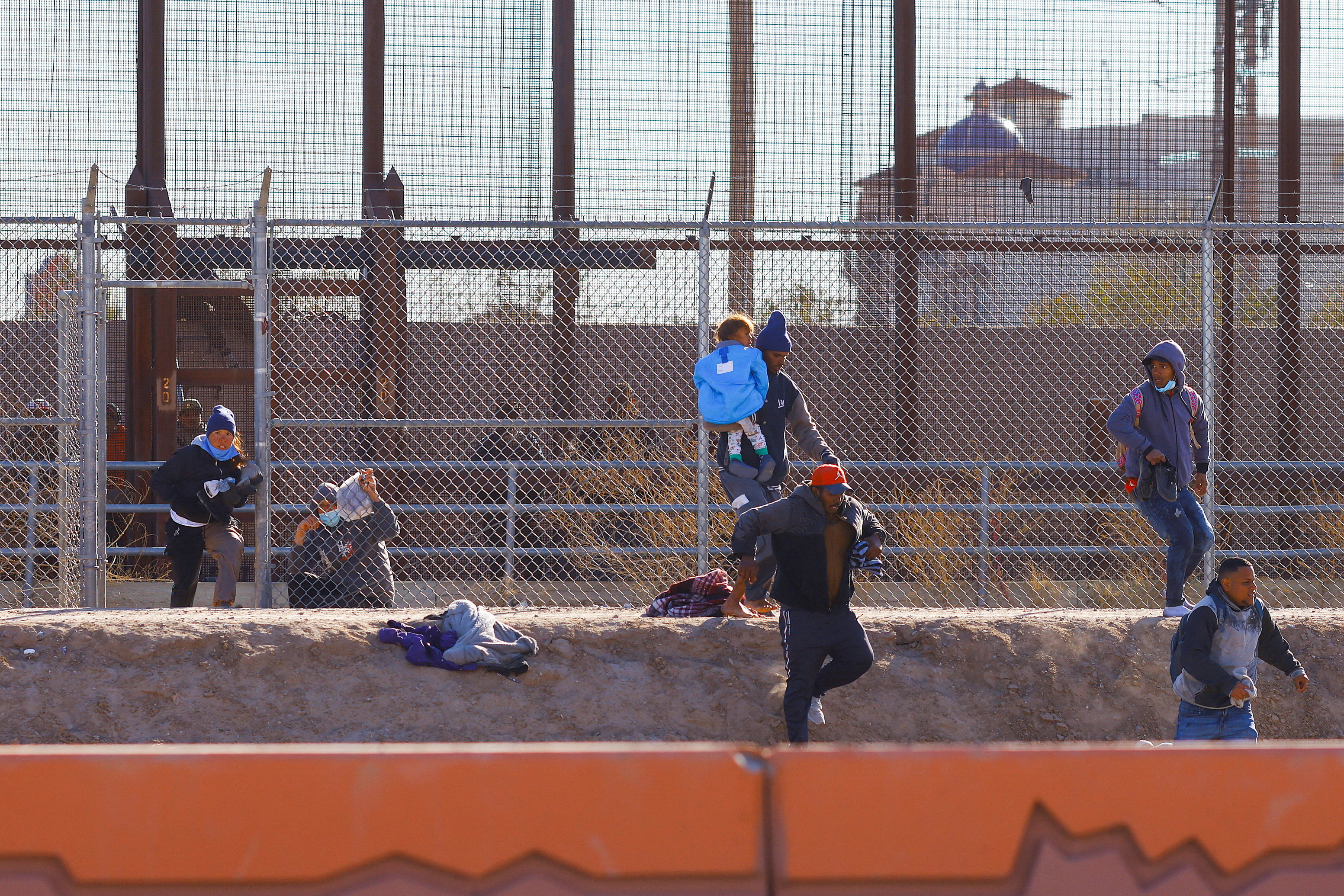 Migrants run to hide from the U.S. Border Patrol and Texas State Troopers after crossing into the United States from Mexico, in El Paso, Texas, Dec. 23, 2022.