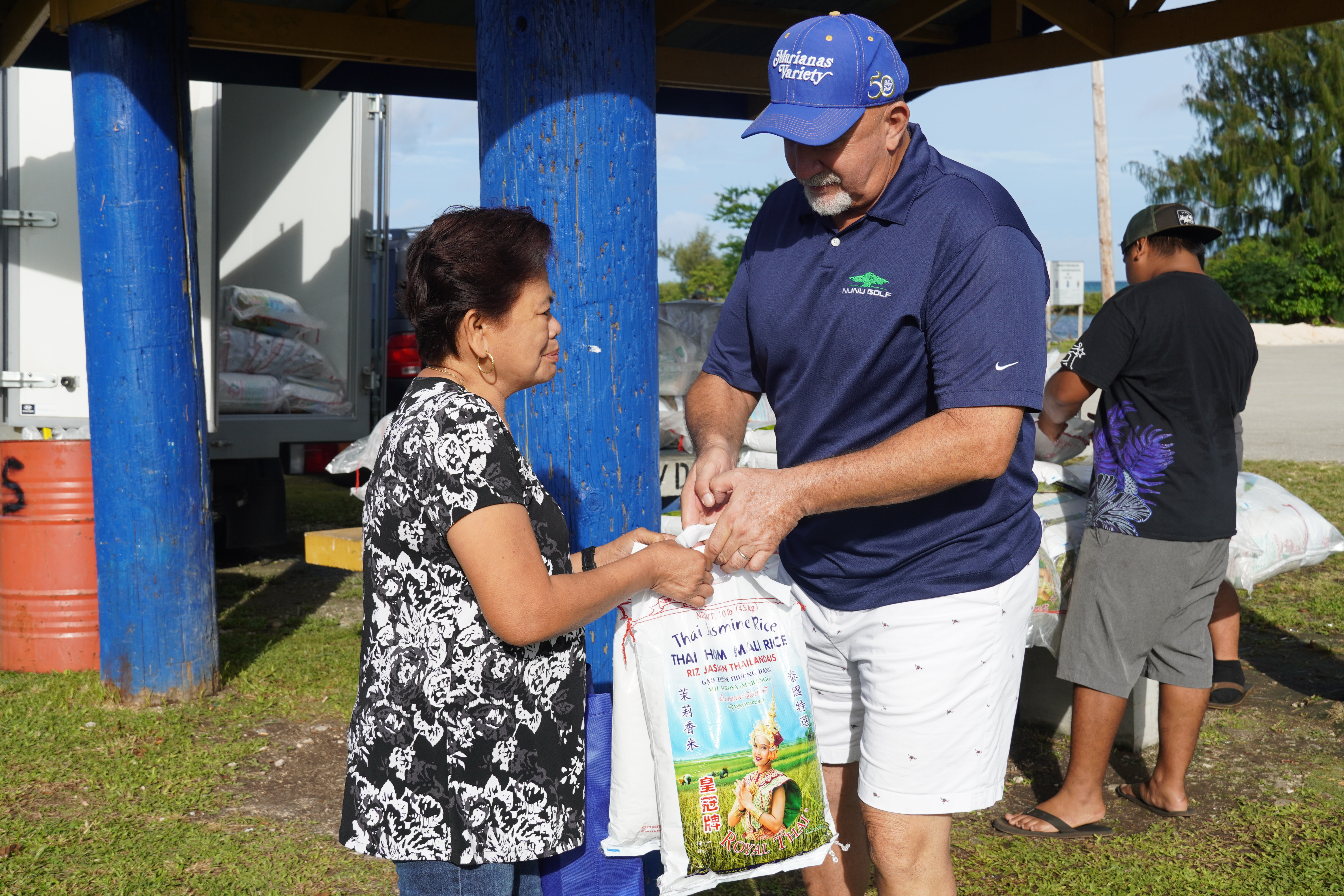 Bridge Capital LLC general manager Bart Johnson gives a free bag of rice to a community member.