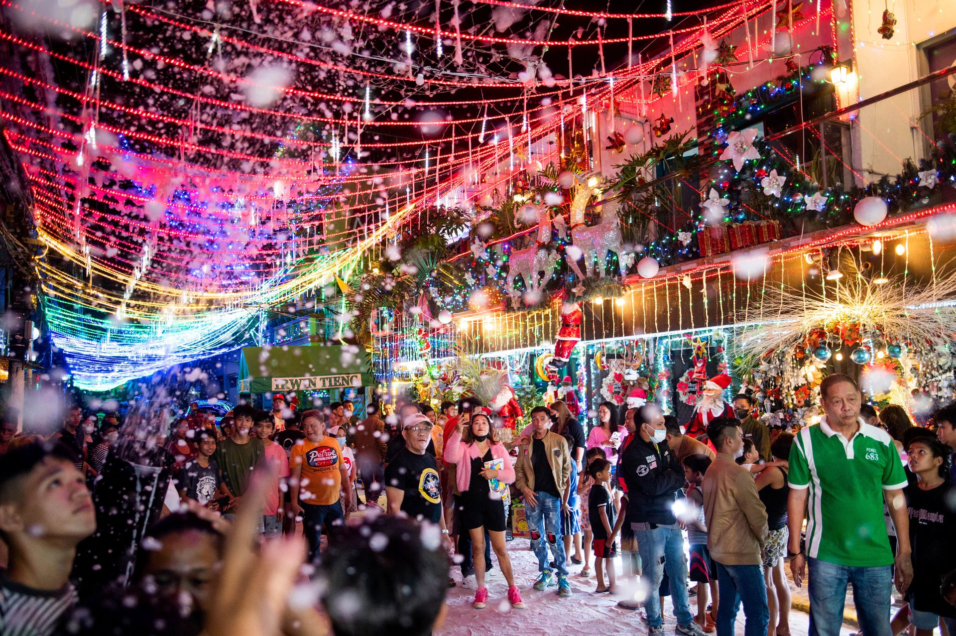 People enjoy fake snow outside a Christmas-themed house, in Manila, the Philippines, Dec. 11, 2022.