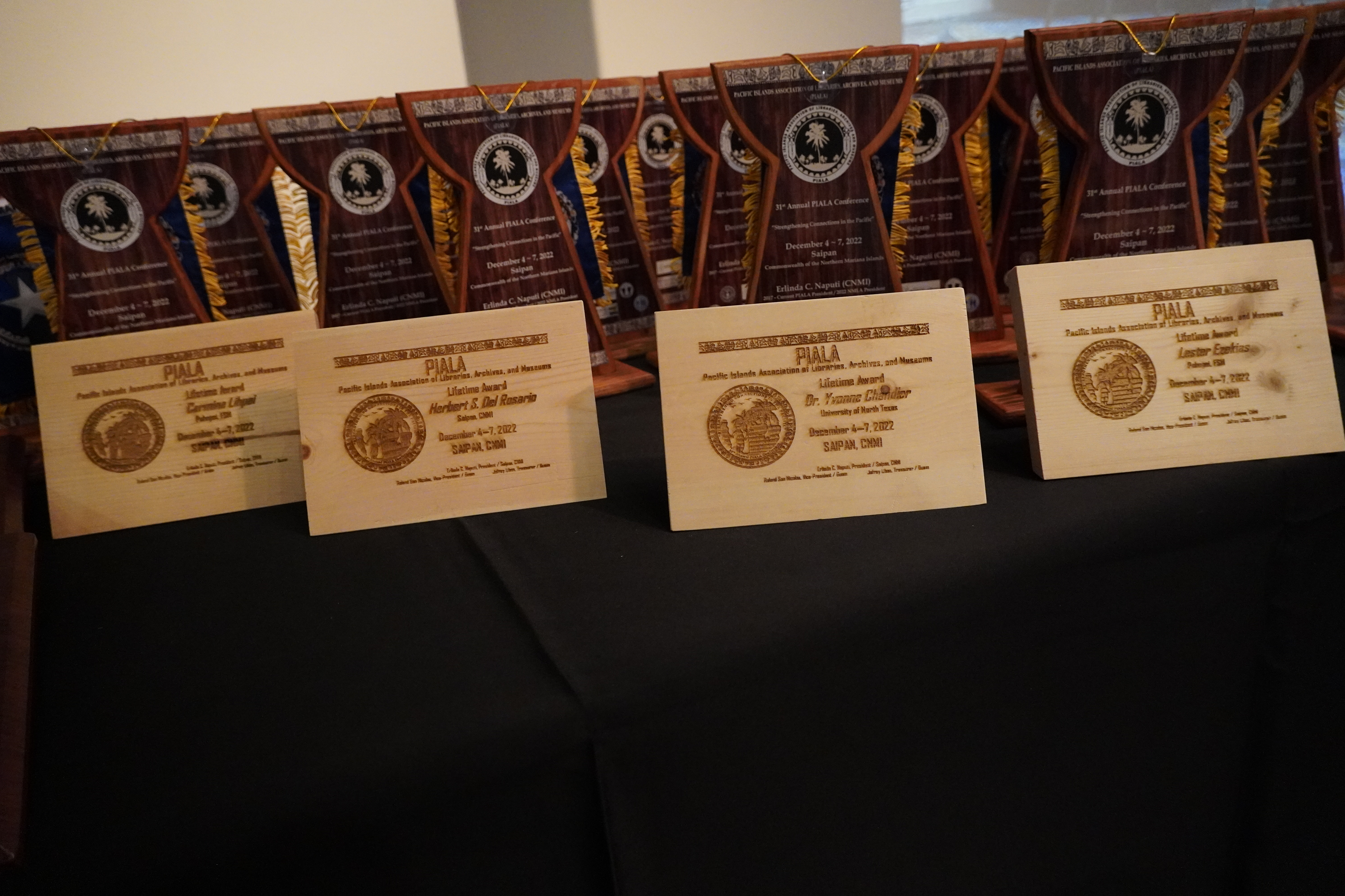 Four PIALA Lifetime Awards sit atop a table, along with other awards