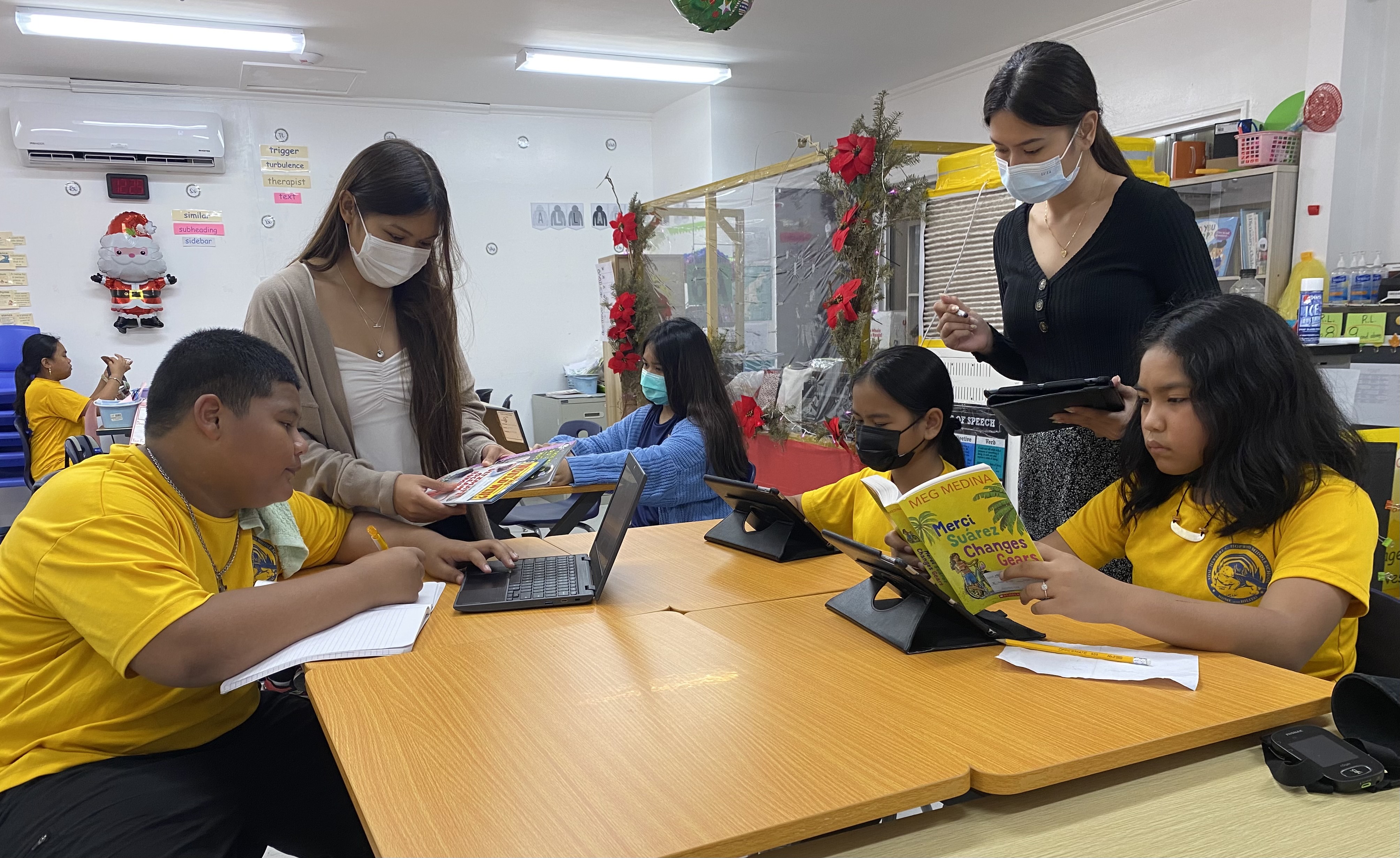 Tutor Christine Beceril, standing left, and a classroom teacher are seen with Hopwood Middle School students.