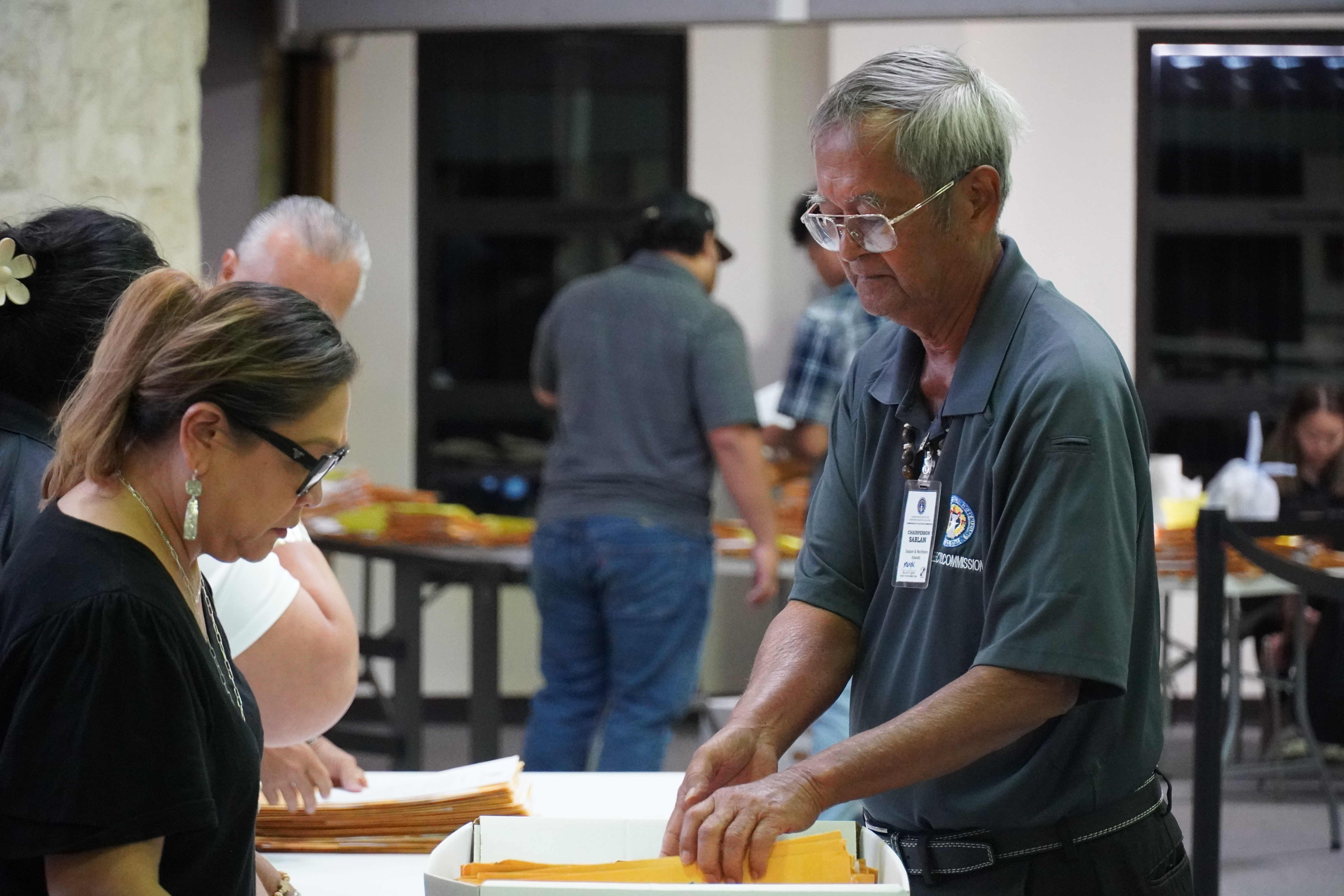 Election board chair Jesus I. Sablan pulls out absentee ballots from a box, before handing stacks to each of the election commissioners.