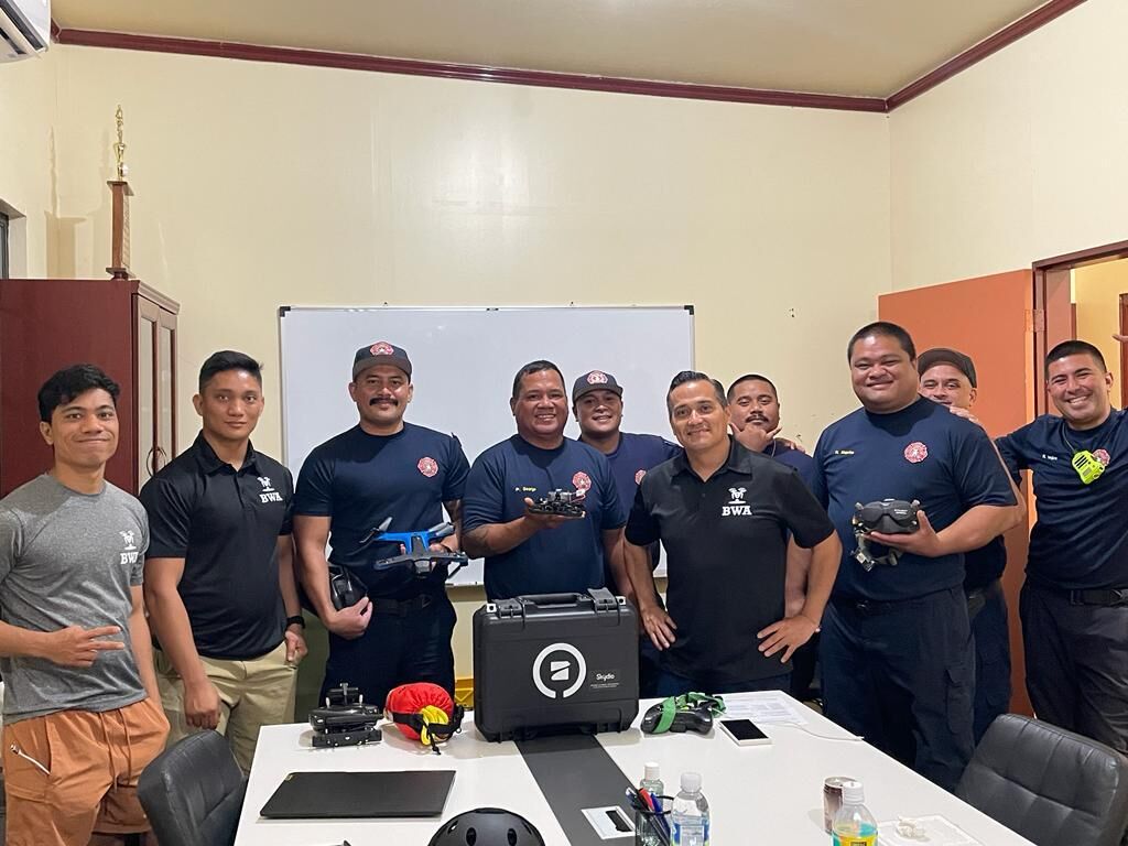 Bella Wings Aviation team members and fire department officials pose for a photo while holding drones.