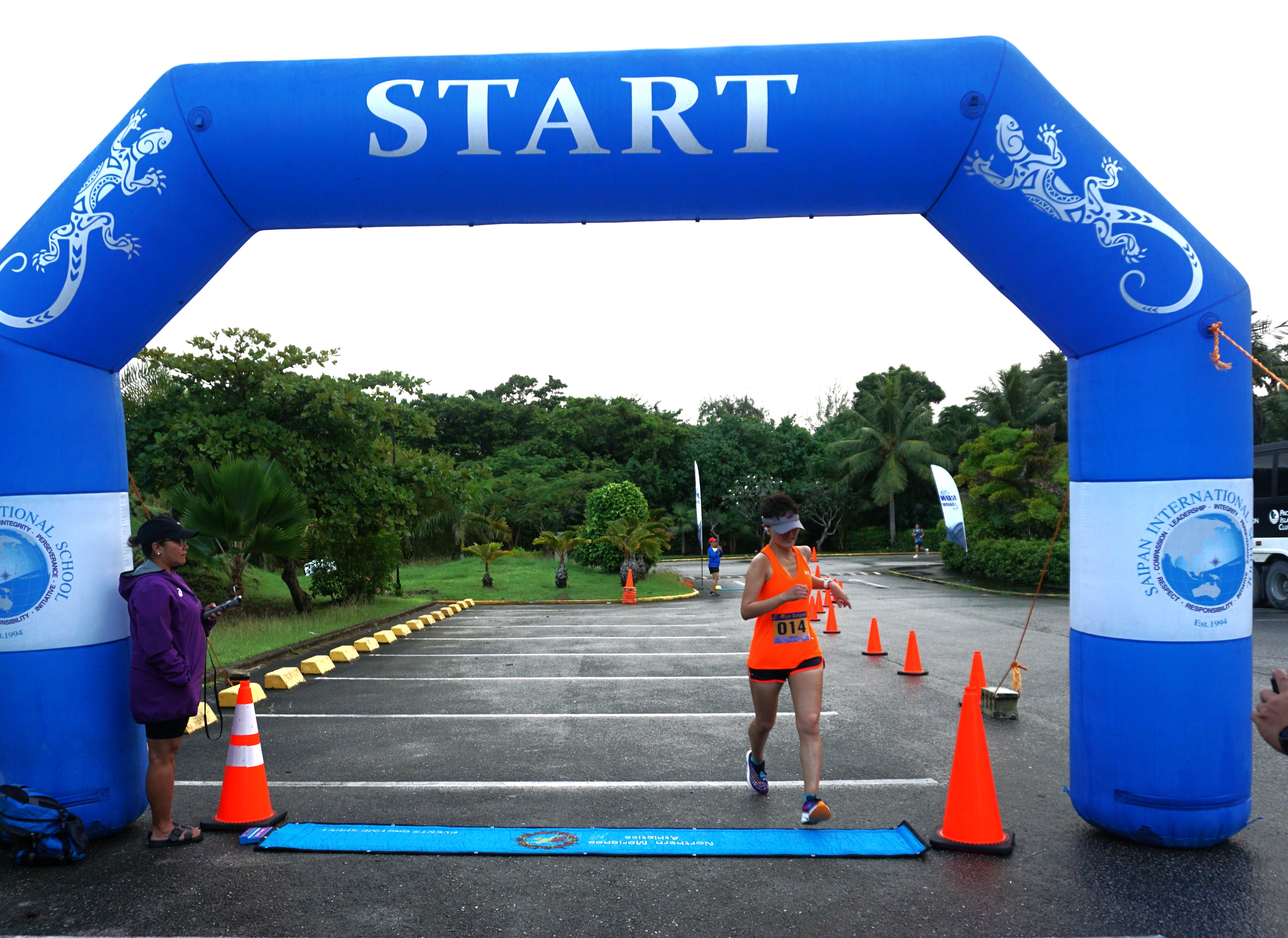 Ann Bang reaches the finish line to rule the women's division of the inaugural Run Saipan Trinity race, Day 1, in the Kensington Hotel upper parking lot on Saturday.
