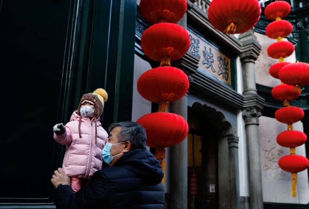 An elderly person holds a child near lanterns decorating a shop ahead of the Chinese Lunar New Year, in Beijing, China, Jan. 15, 2023.