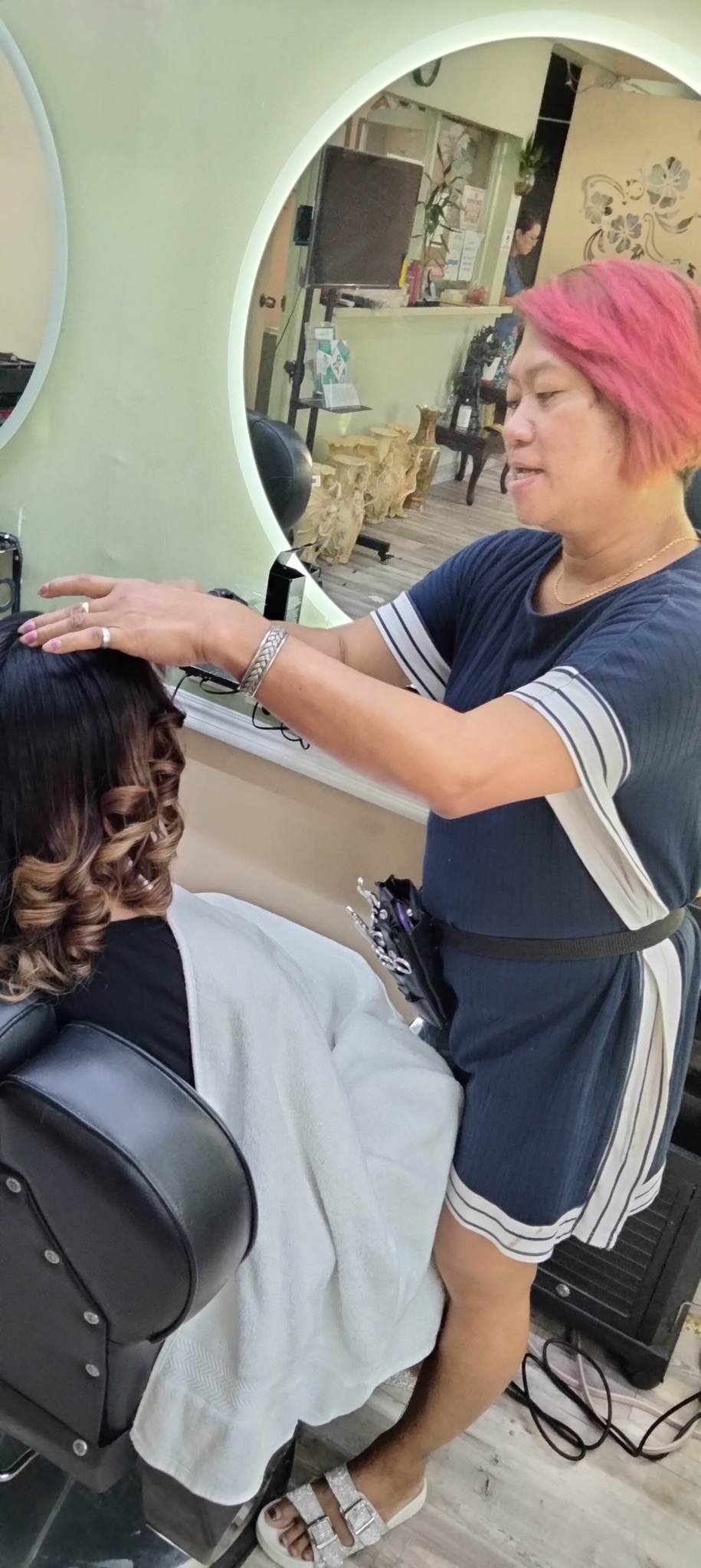 Beautician Joan Olivero styles the hair of a client at Creative Salon and Spa in Chalan Kanoa.