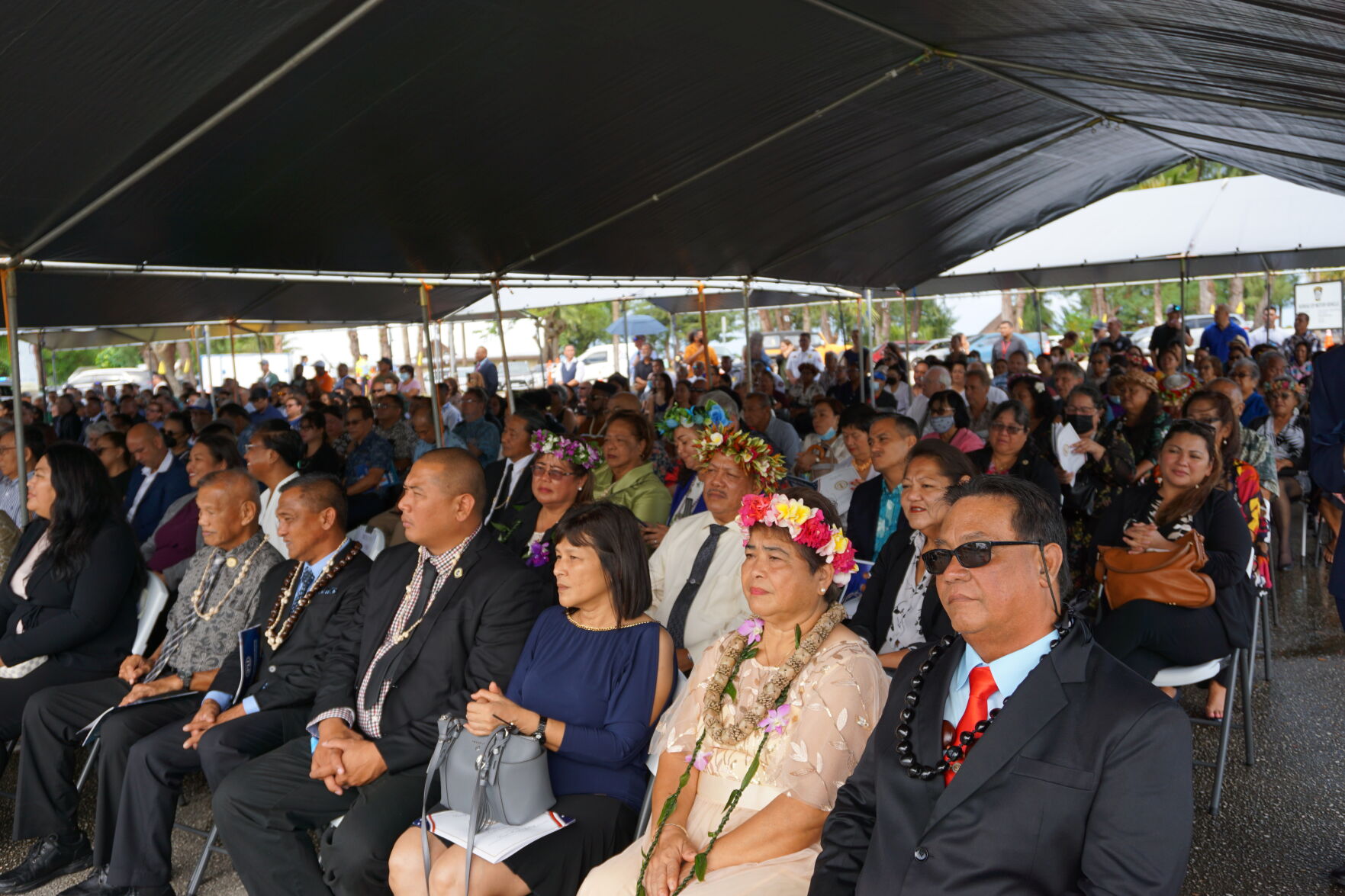 Dignitaries and community members are seated under a canopy during the inaugural ceremony.