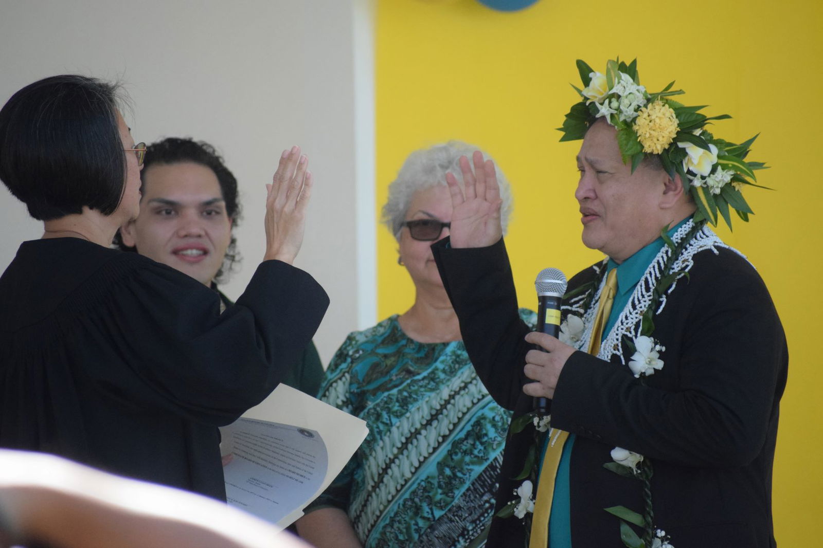 Board of Education member Andrew L. Orsini, right, is sworn in by Associate Judge Teresa Kim-Tenorio, left, as his wife Bertha, 2nd right, and son Romolor look on during his inauguration at Oleai Elementary School on Friday.