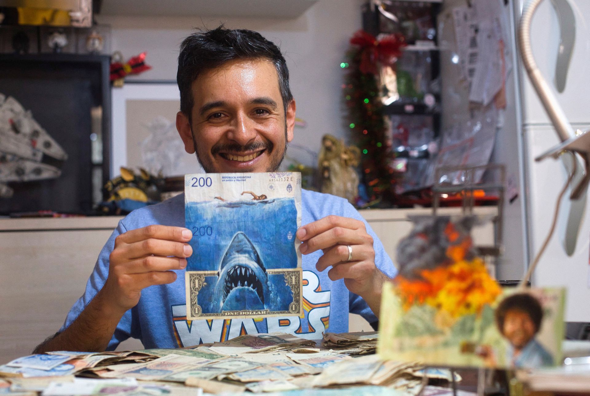 Artist Sergio Diaz holds Argentine pesos bills and a U.S. dollar depicting Steven Spielberg's movie "Shark" as a parody of Argentina's ever-increasing inflation, in Salta, Argentina, Dec. 30, 2022.
