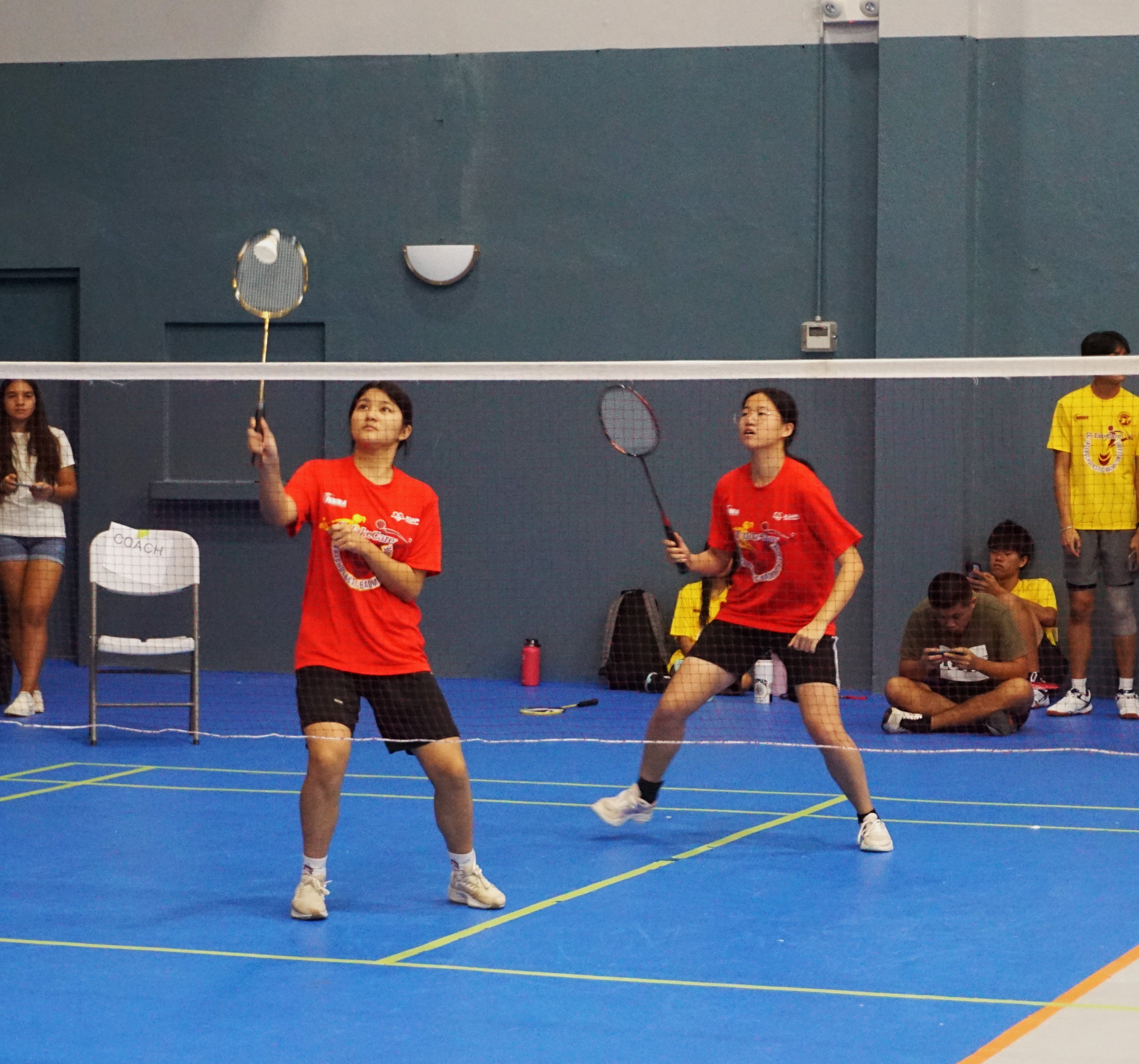 ACS 1's Tina Zheng connects the return as teammate Susie Zheng looks on during a girls doubles event of the NMBA-PSS Interscholastic Badminton League on Saturday at the Ada gym.