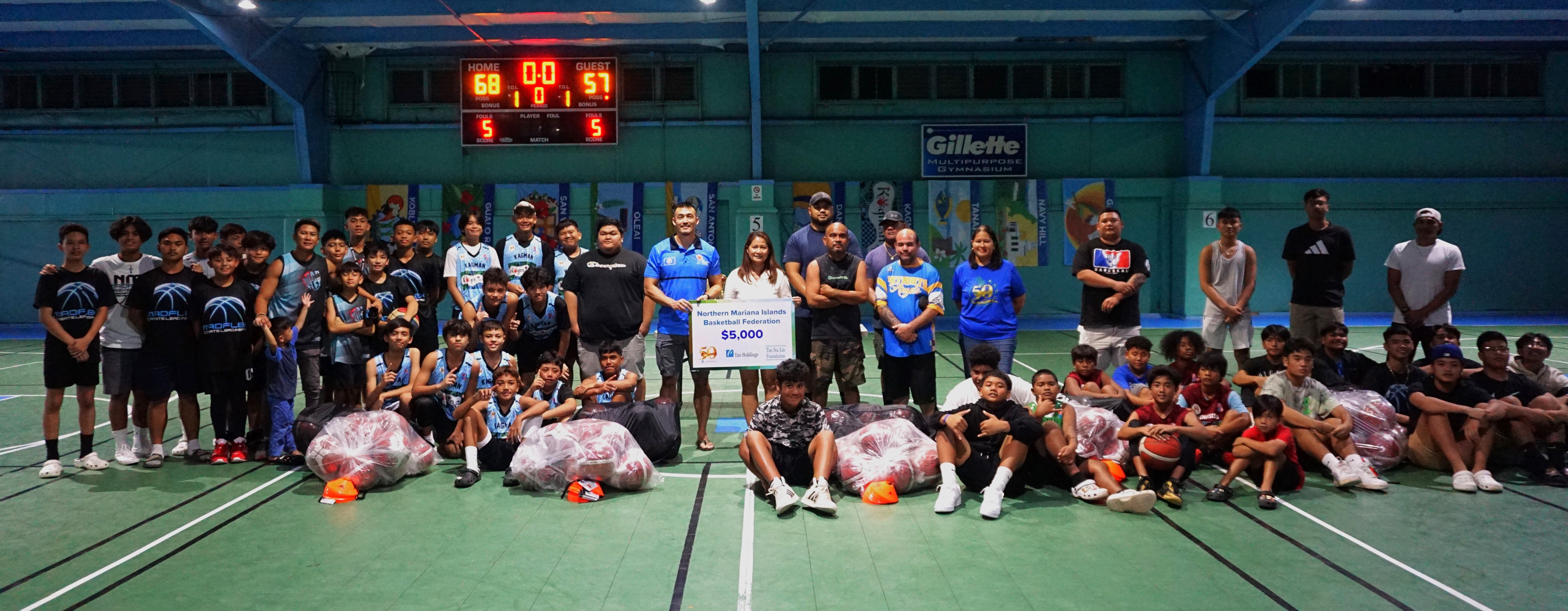 Tan Siu Lin Foundation Executive Director Merlie Tolentino, Northern Mariana Islands Basketball Federation President James Lee,  and Tan Holdings Vice President for Corporate Affairs Catherine Attao-Toves pose with the representatives of five local basketball clubs that received equipment from Tan Holdings in celebration of its 50th anniversary on Sunday at the TSL Sports Complex.