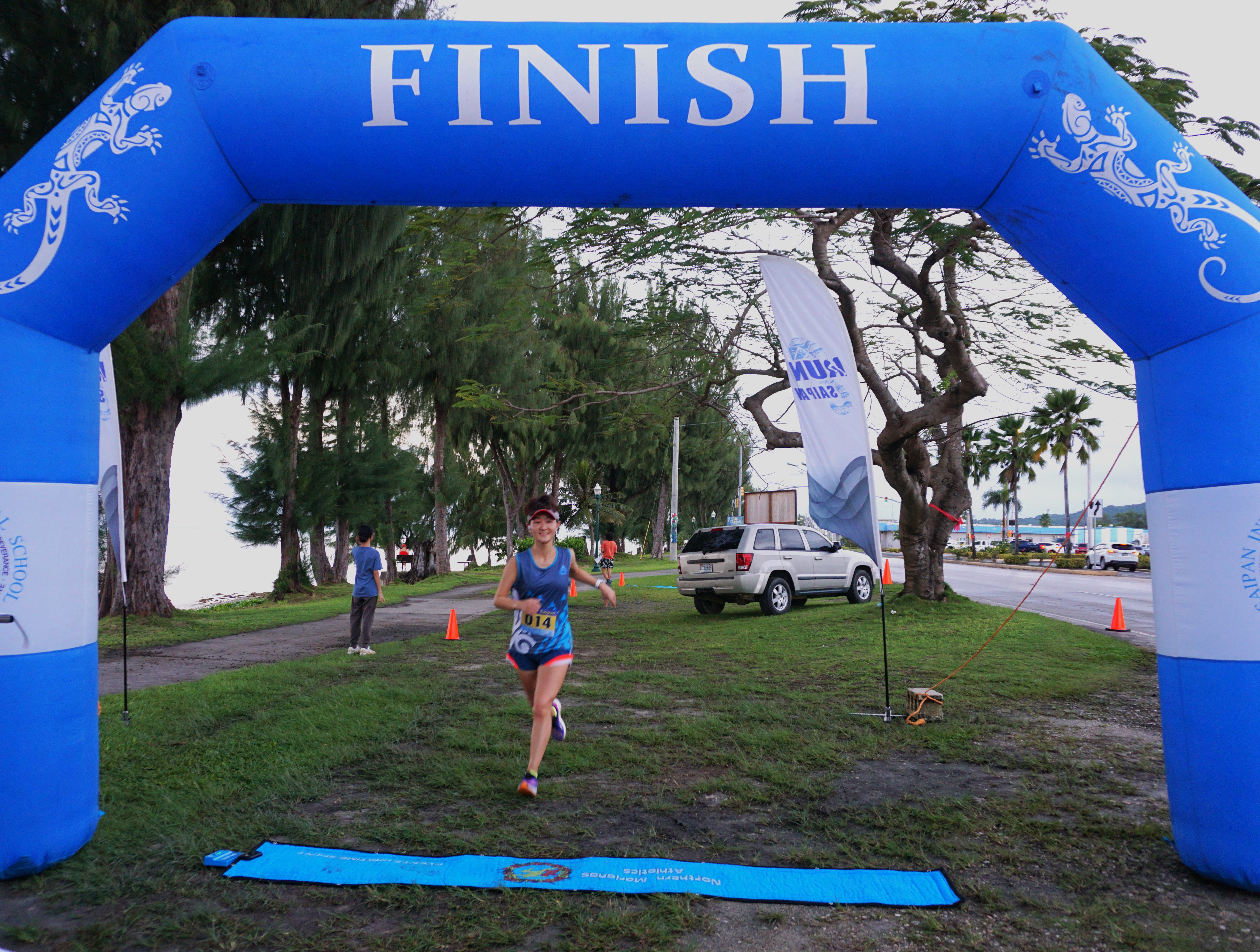 Ann Bang smiles as she crosses the finish line to finish first on  Day 3 of the Run Saipan Trinity event Monday on  Beach Road in Oleai