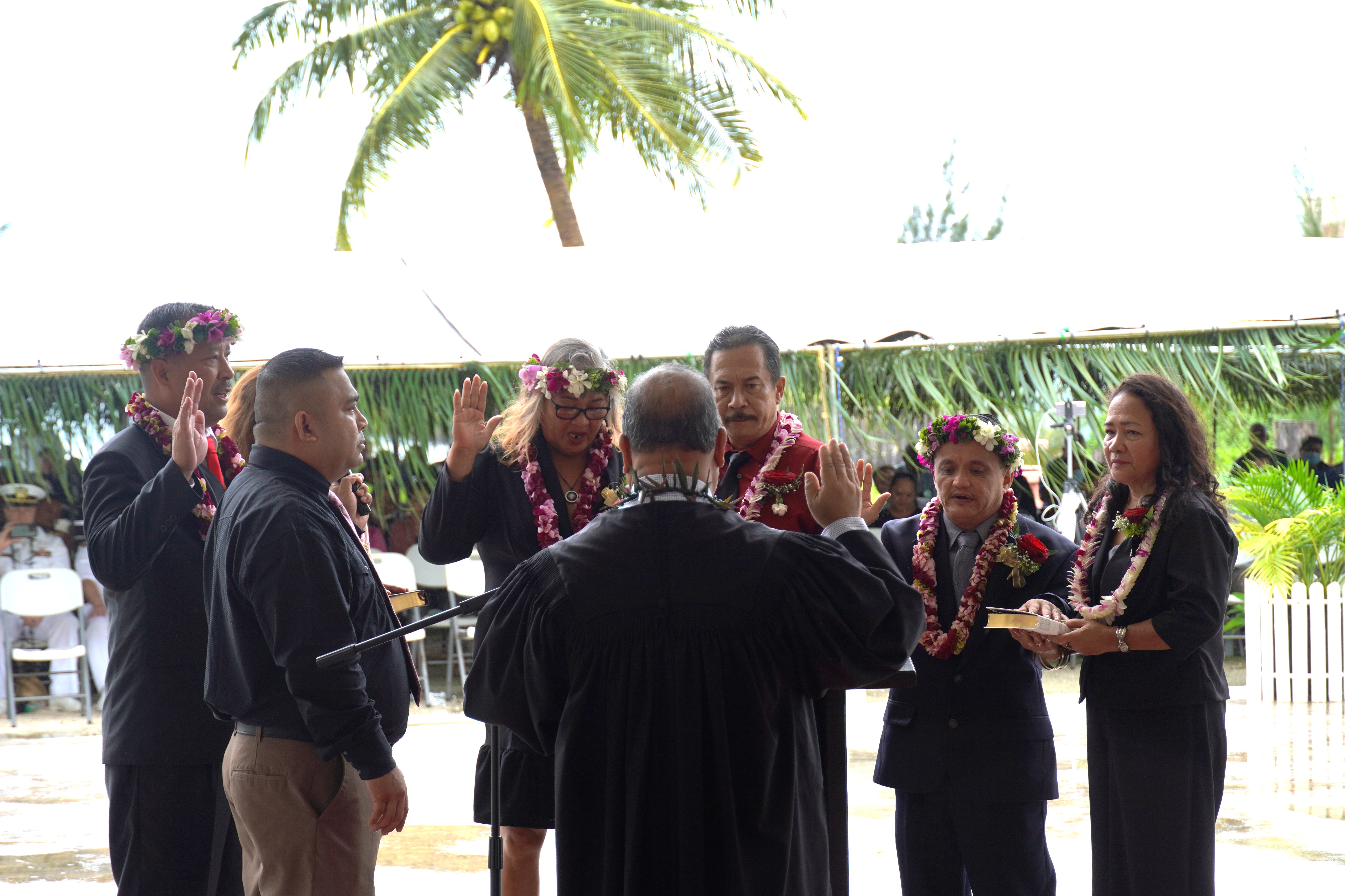 19th Municipal Council chair Joseph Romaldo Evangelista Santos, far left, vice chair Ana Marie Cruz San Nicolas, third left, and secretary Estevan Pangelinan Cabrera, second right, take their oaths of office, administered by Justice Perry B. Inos, back facing camera. The councilmembers' spouses hold their Bibles, while master of ceremonies Eric J. Reyes, second left, holds a microphone for the councilmembers. The inaugural ceremony was held Friday, Jan. 13 at the main pavilion of Jones Beach in San Jose, Tinian.