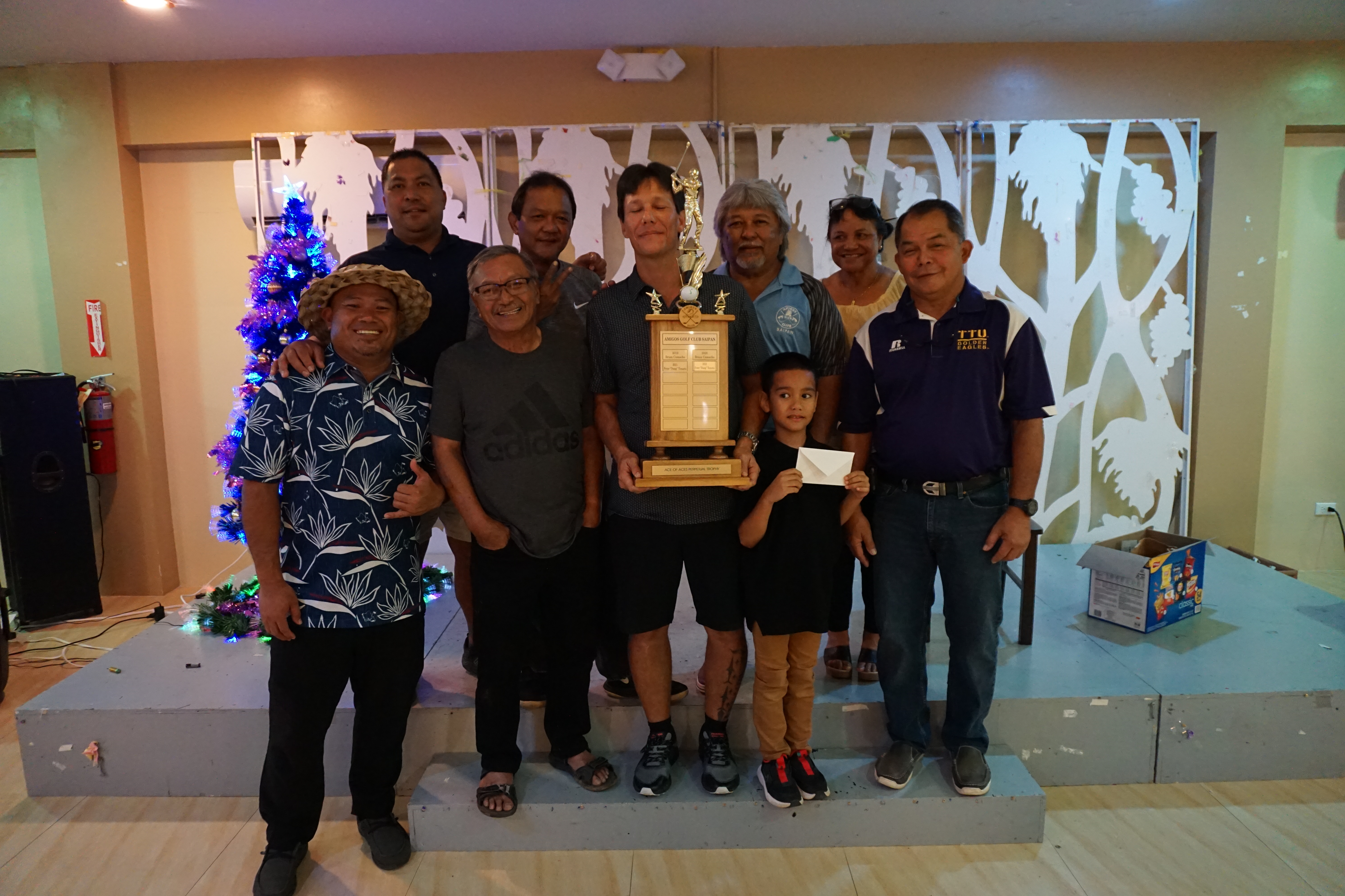 Dung Tenorio holds the Ace of Aces perpetual trophy as he poses for a photo with the  Amigos Golf Club officers during a banquet at the Rendezvous Restaurant of Saipan Vegas.