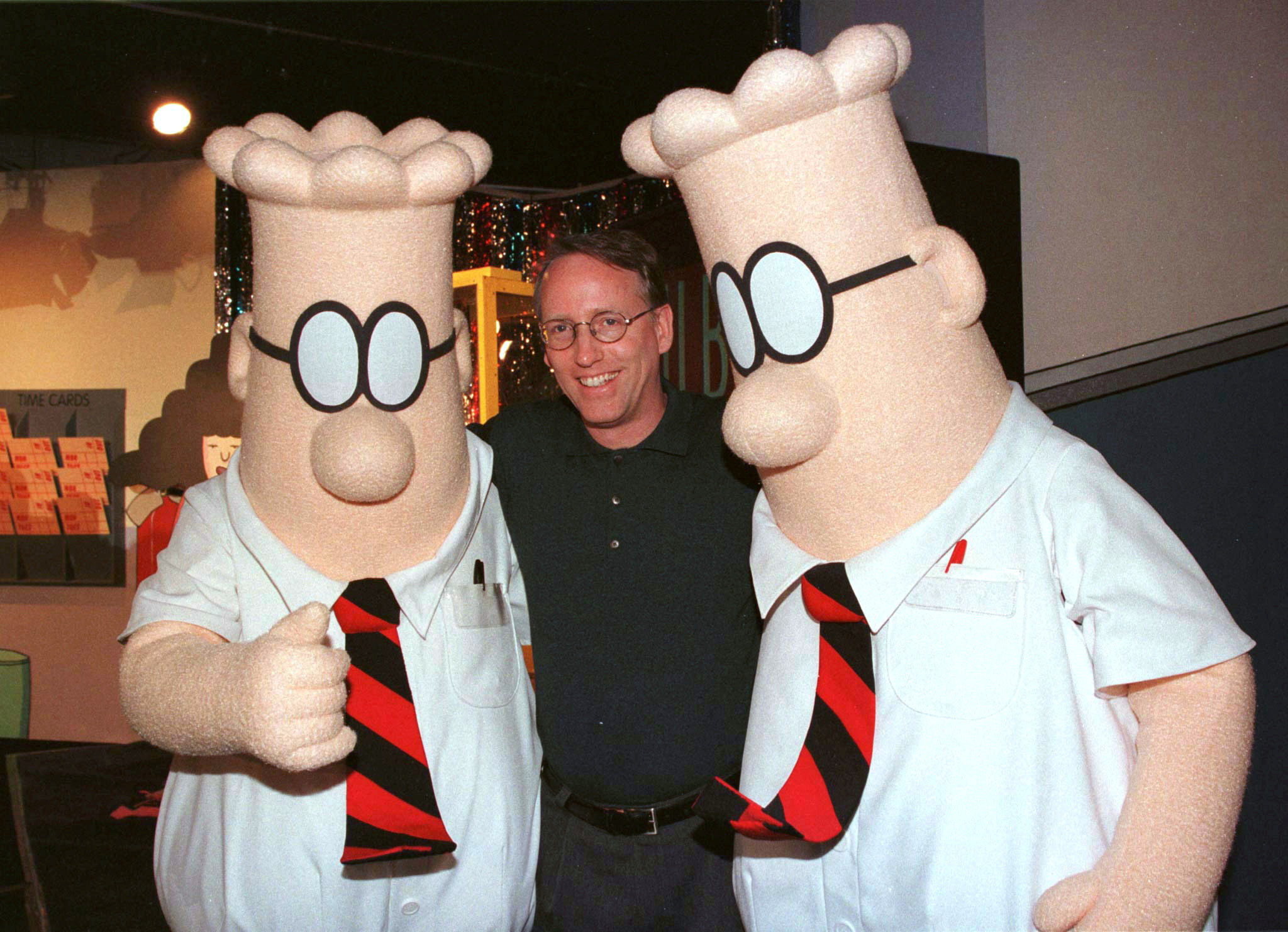 Scott Adams, the creator of "Dilbert," the cartoon character that lampoons the absurdities of corporate life, poses with two "Dilbert" characters at a party on Jan. 8, 1999 in Pasadena, Calif.