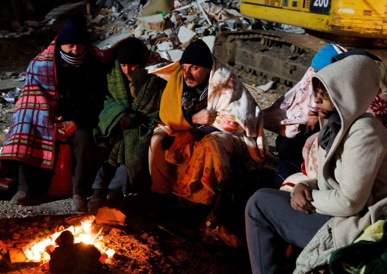 Zubeyde Kahraman, right, whose sister Zeynep, 40, is being rescued by ISAR Germany, waits by a fire with her family during the rescue operation that ISAR Germany say has taken almost 50 hours, as the search for survivors continues, in the aftermath of a deadly earthquake in Kirikhan, Turkey, Feb. 10, 2023.