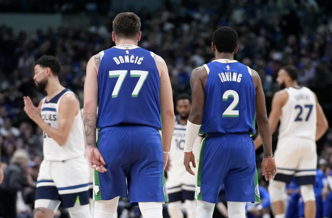 Dallas Mavericks' Luka Doncic (77) and Kyrie Irving (2) talk at mid court during the first half of an NBA basketball game against the Minnesota Timberwolves, Monday, Feb. 13, 2023, in Dallas.