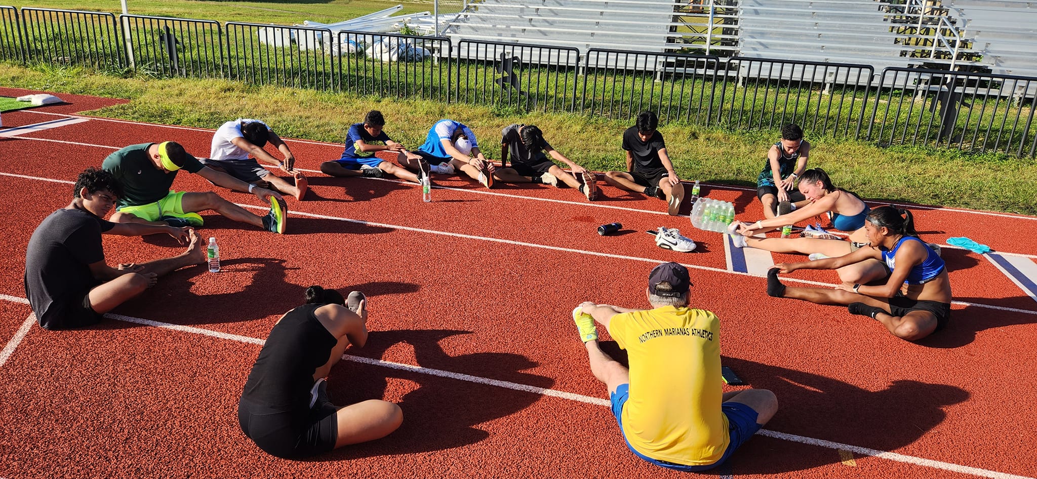 Participants stretch before performing drills on the first day of the Northern Marianas Athletics Talent ID Camp Saturday at the track and field of the Oleai Sports Complex.