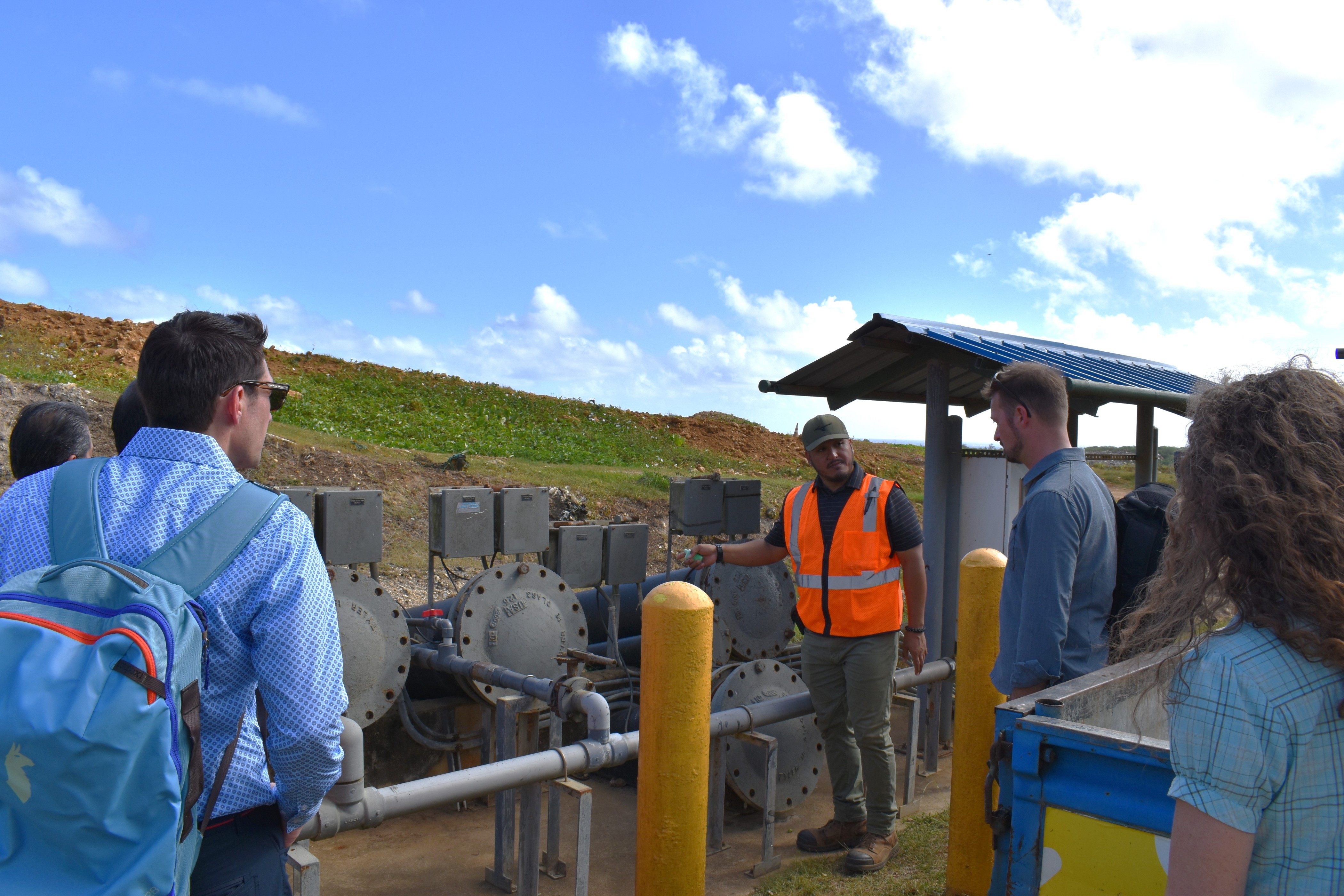Project Manager for Micronesian Environmental Services, LLC James Benavente, third from right, points out a landfill leachate pump and the existing electrical systems that power it during a tour of the Marpi Landfill for representatives from the U.S. Department of Energy  and the Pacific Northwest National Laboratory. 