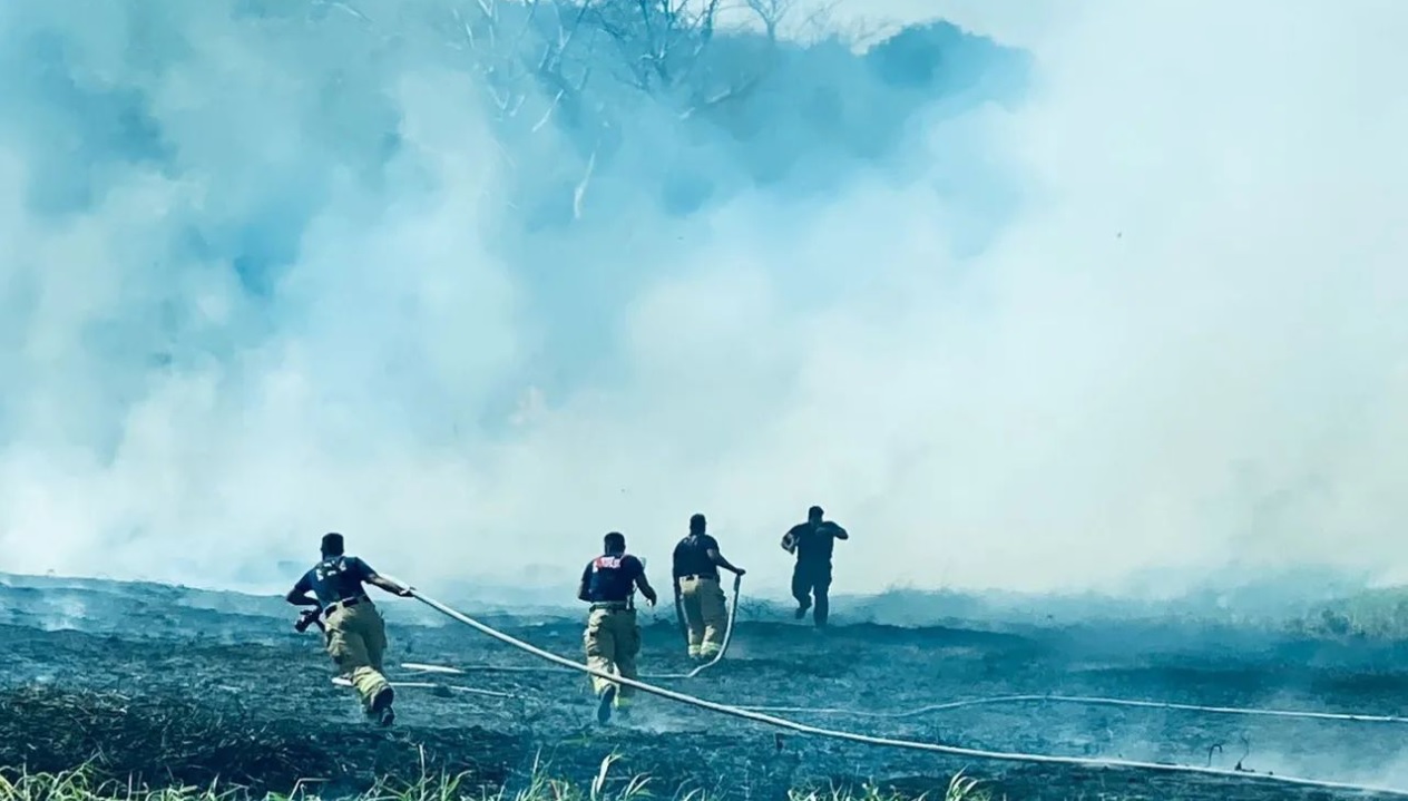 Firefighters try to extinguish a grassfire near the former Kan Pacific swimming pool in Marpi on Monday.