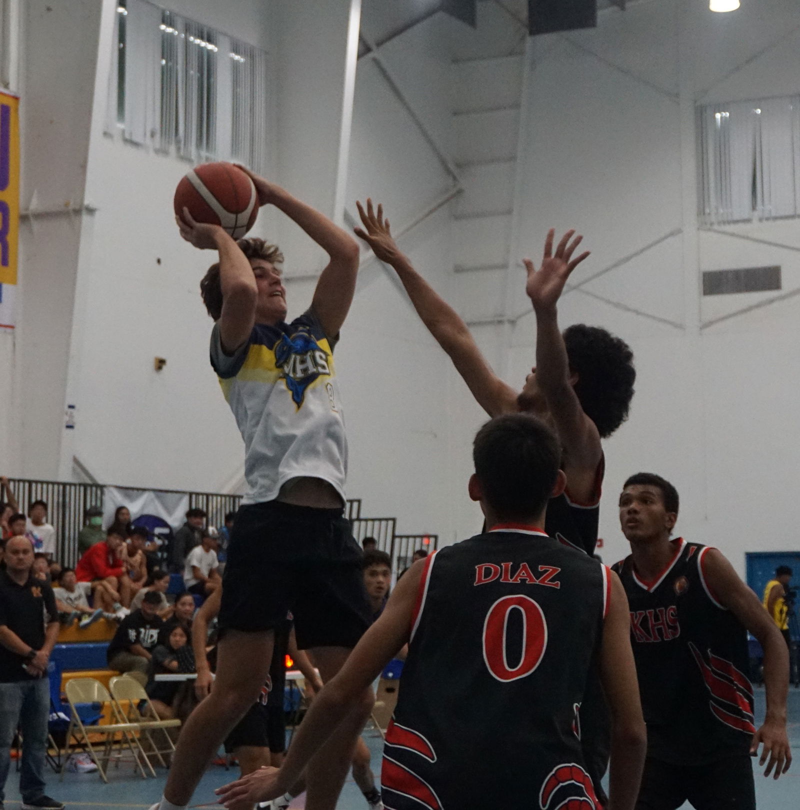 MHS' Dylan Mister attempts the fadeaway shot against three KHS defenders during  the boys high school division championship game of the IT&E Interscholastic Basketball League on Saturday at the MHS gym.