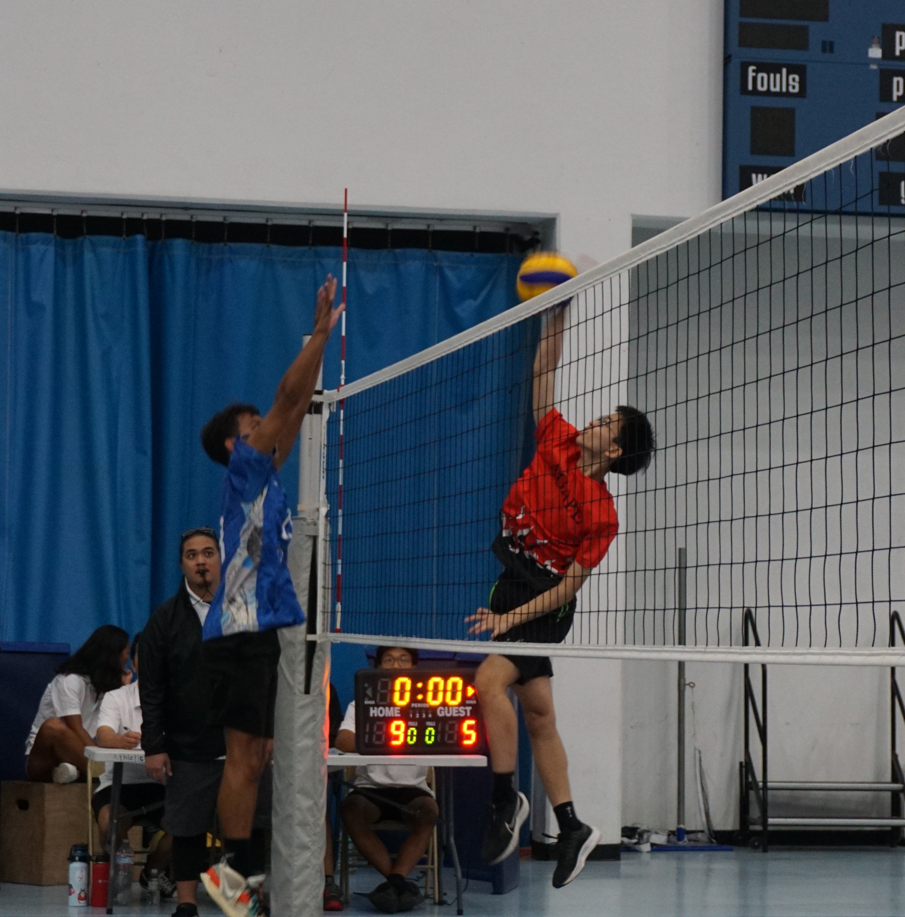 ACS' Ziqian Cheng connects a spike against an SIS defender during the boys middle school division championship match of the NMIVA-PSS Interscholastic Volleyball League on Saturday at the MHS gym.
