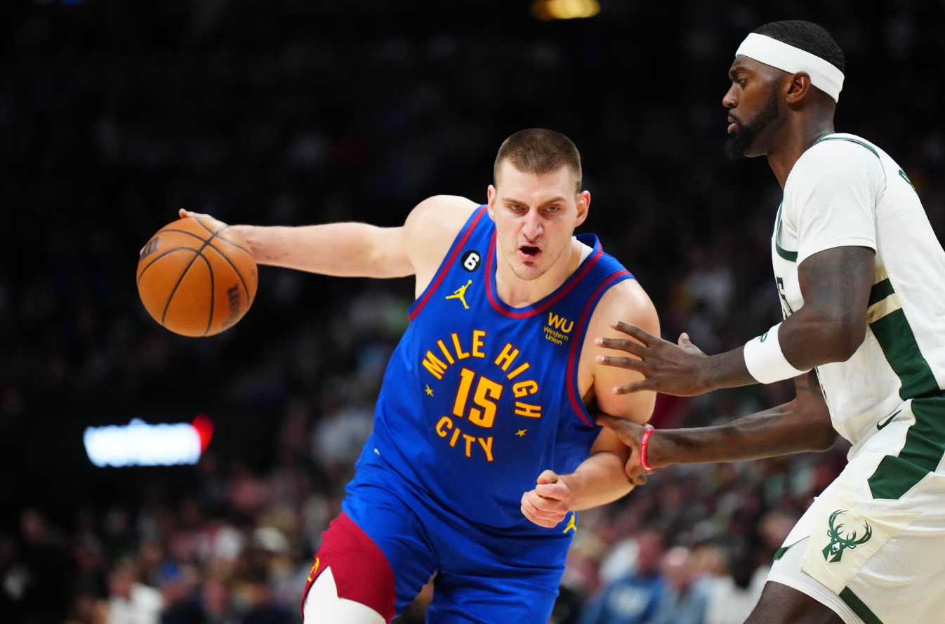 Denver Nuggets center Nikola Jokic (15) drives at Milwaukee Bucks forward Bobby Portis (9) during the second half at Ball Arena in Denver, Colorado, March 25, 2023.