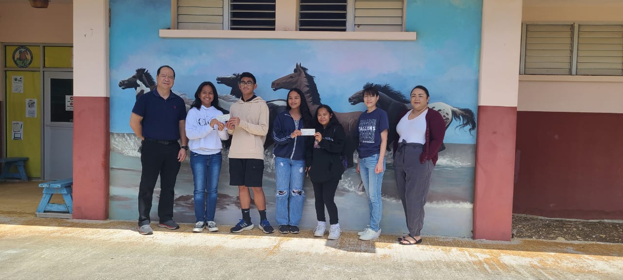 Sofia Del Rosario and Adriel Lenteja, second and third left, respectively, receive $500 on March 8, 2023, at Tinian Jr./Sr. High School for 1st place in the Marianas Tourism Education Council Tourism App Challenge. Also awarded for 3rd place and receiving $200 are Bernadette Fleming and Carrika San Nicolas, center and third right, respectively. From left are MTEC Board Member Martin Duenas, Del Rosario, Lenteja, Fleming, San Nicolas, MY WAVE Club Advisor Erica S. Evangelista and Vice Principal Nikita Mendiola.