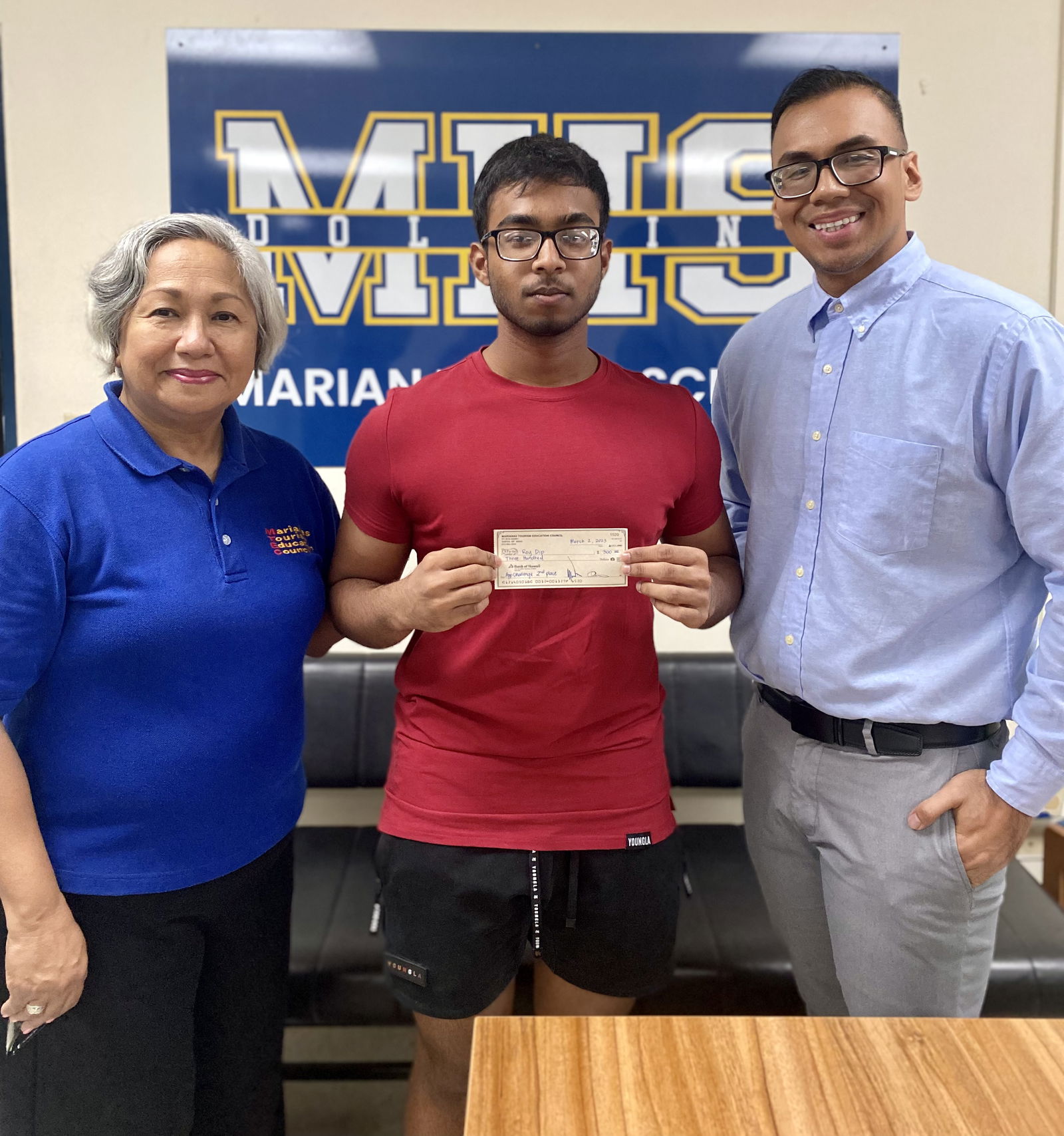 Dip Roy, center, received $300 on March 9, 2023, at Marianas High School for 2nd place in the Marianas Tourism Education Council Tourism App Challenge.  From left, MTEC Acting Chairwoman Vicky Benavente, Roy, and Marianas High School Principal Jonathan Aguon.