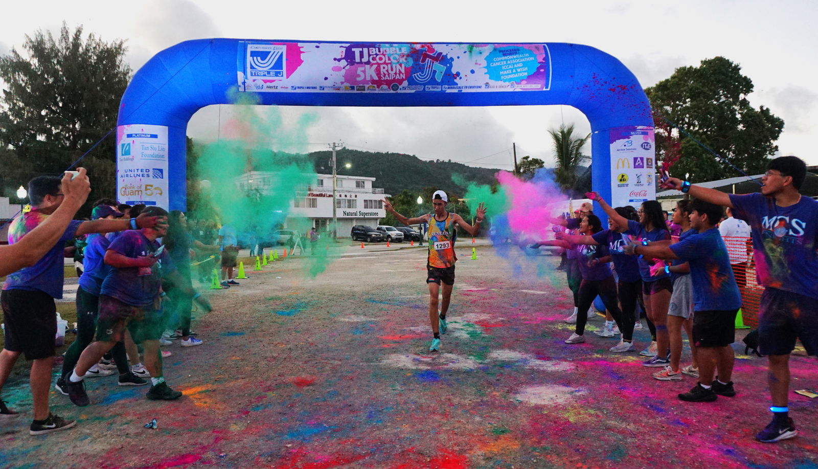 Mount Carmel School students throw colored powder at Sildrey Veloria as he crosses the finish line of the 3rd Annual Triple J 5K Bubble Color Run on Saturday at the Garapan Fishing Base.