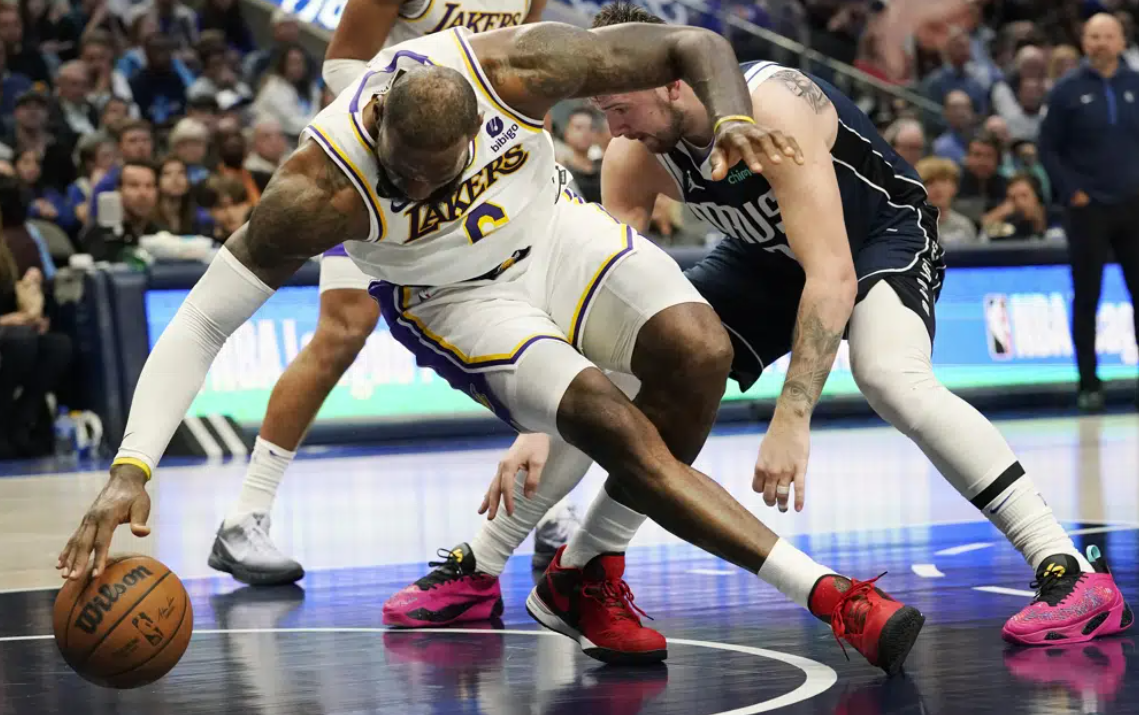 Los Angeles Lakers forward LeBron James, left, reaches for the ball against Dallas Mavericks guard Luka Doncic, right, during the second half of an NBA basketball game in Dallas, Sunday, Feb. 26, 2023.