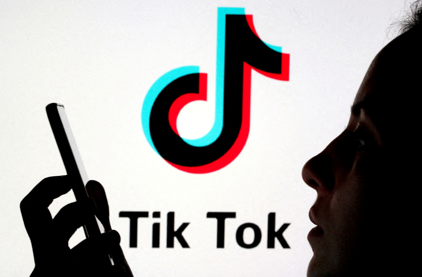 A person holds a smartphone as TikTok logo is displayed behind in this picture illustration taken Nov. 7, 2019.