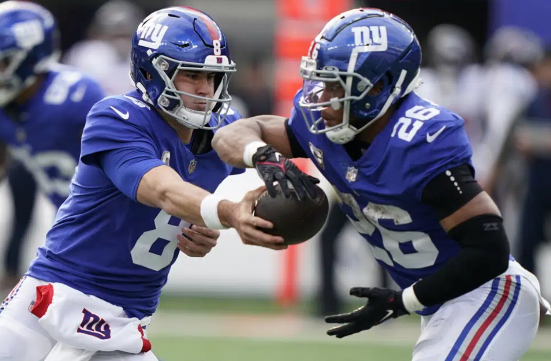 New York Giants quarterback Daniel Jones (8) hands off the ball to New York Giants running back Saquon Barkley (26) during the second quarter of an NFL football game, Sunday, Nov. 13, 2022, in East Rutherford, N.J.
