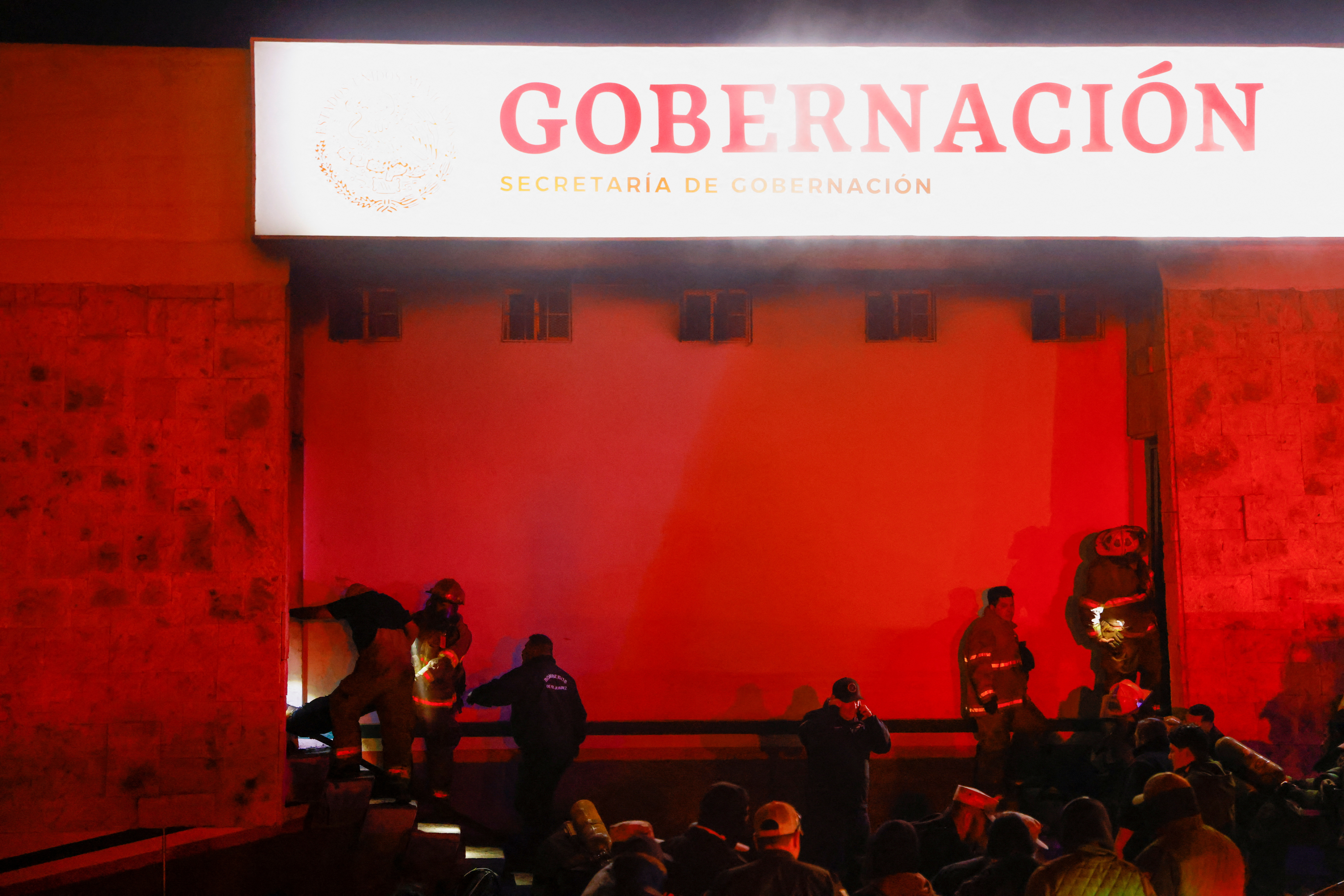 Mexican authorities and firefighters remove injured migrants, mostly Venezuelans, from inside the National Migration Institute building during a fire, in Ciudad Juarez, Mexico, March 27, 2023.