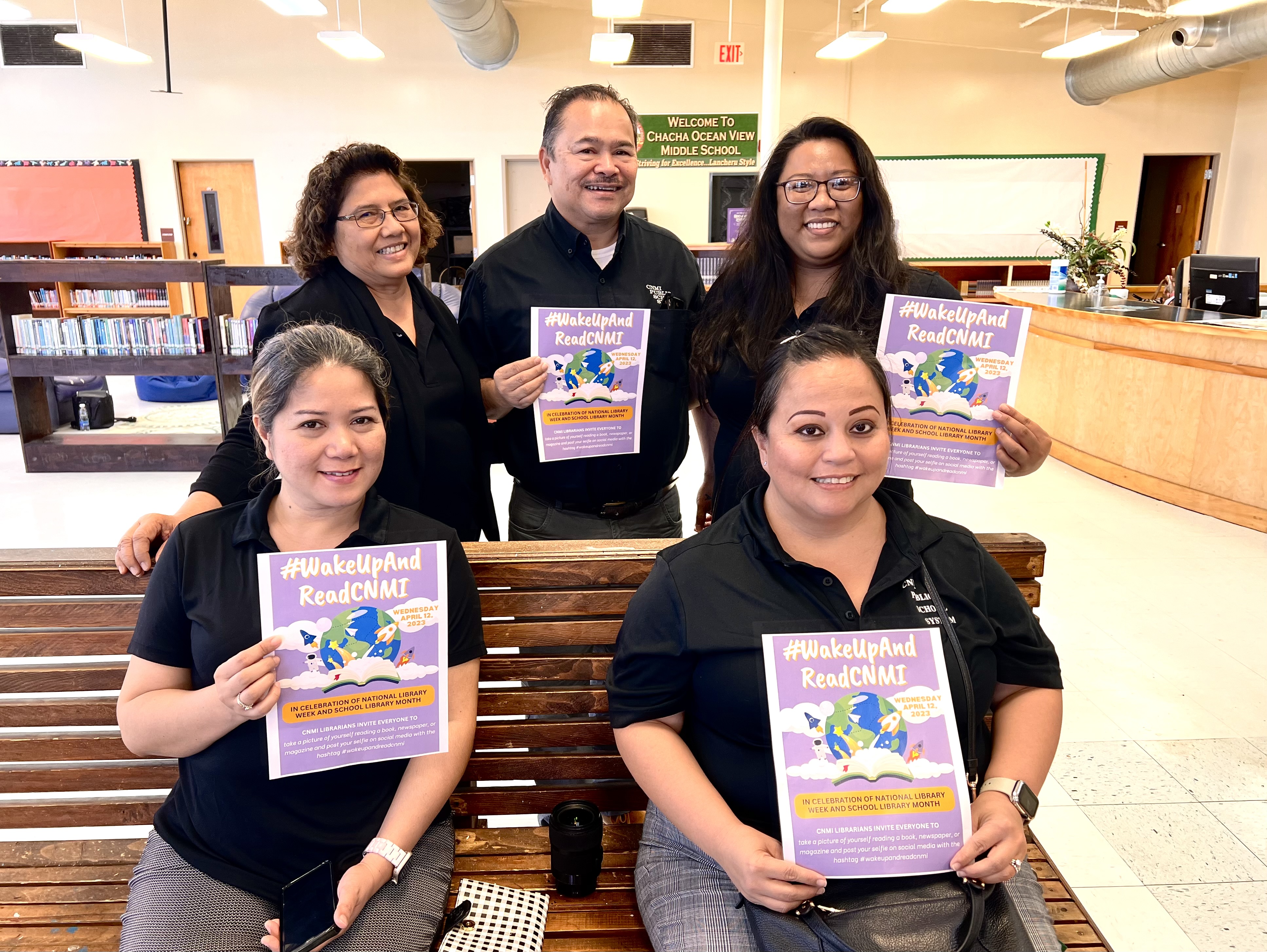 Commissioner of Education Dr. Alfred B. Ada, Public School System Senior Director for Curriculum and Instruction Jackie Quitugua, Finance and Budget Director Arlene Lizama, Human Resources Officer Lucretia Deleon Guerrero and Instructional Technology and Distance Education interim Director Lorraine Catienza display the #wakeupandreadcnmi flyers honoring public school librarians.
