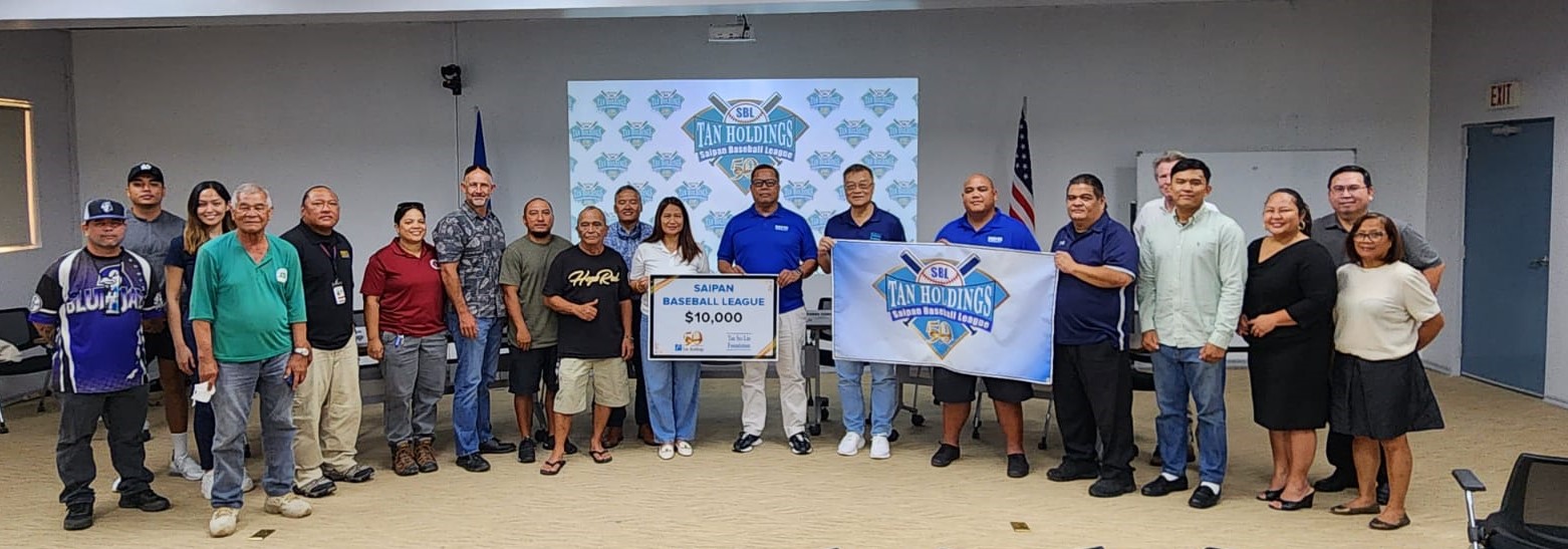 Jay Santos and Jerry Tan, center, pose with Tan Holdings and Saipan Baseball League officials as well as coaches on Wednesday in the Ada gym conference room.
