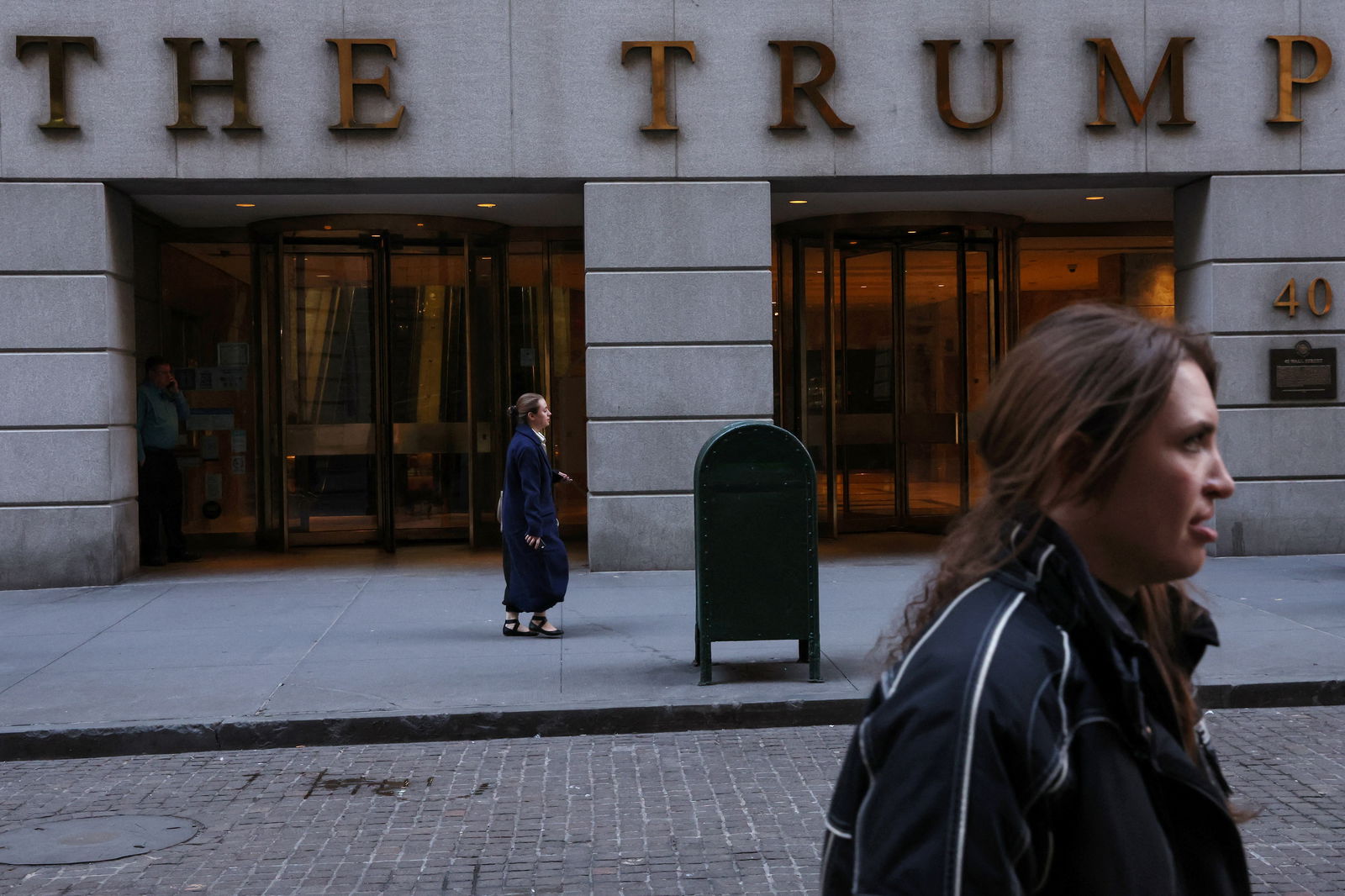People walk by the Trump Building at 40 Wall Street in New York City,  March 21, 2023, after a message was posted on the Truth Social account of former U.S. President Donald Trump stating that he expects to be arrested on Tuesday, and called on his supporters to protest. 