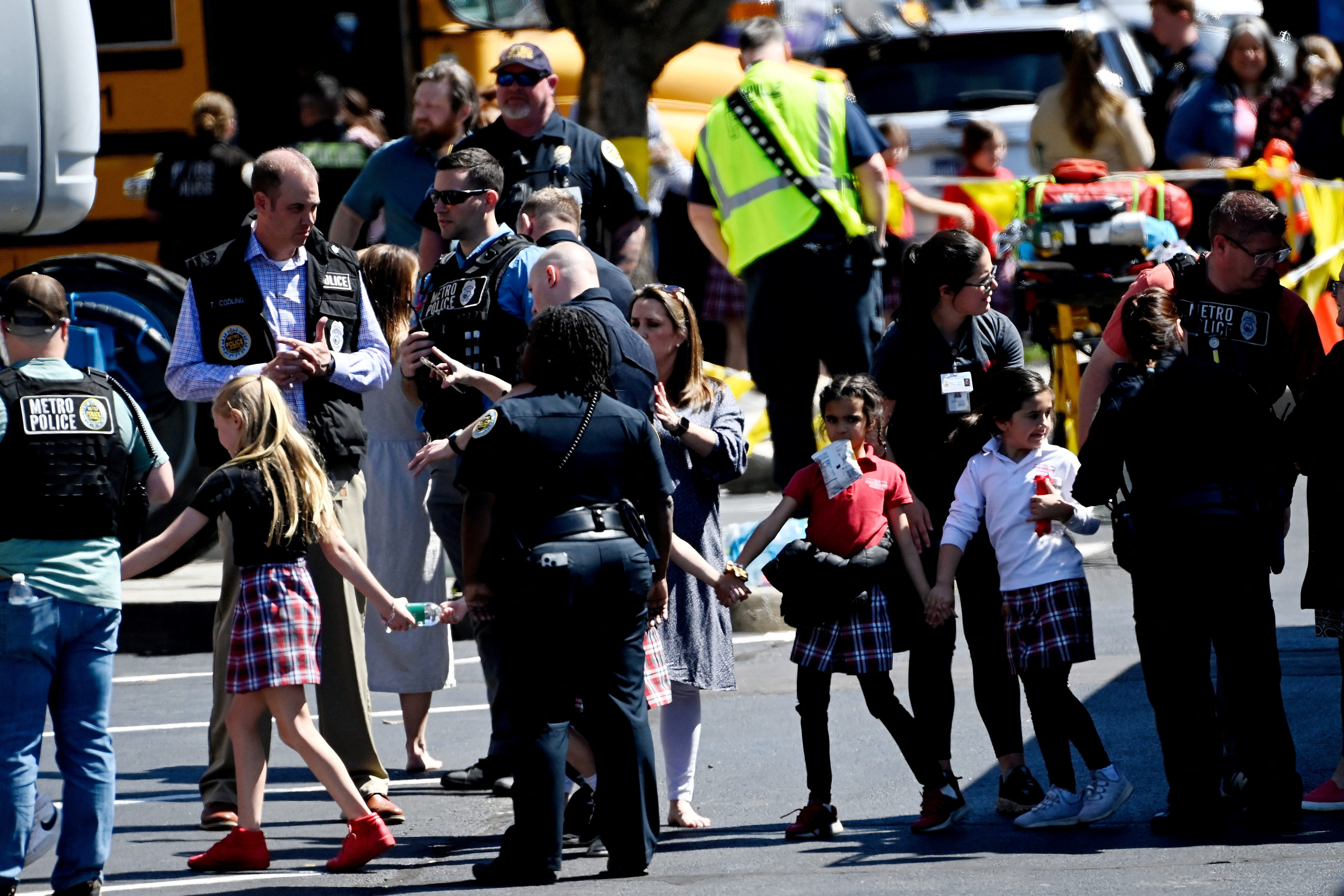 Students from The Covenant School hold hands after getting off a bus to meet their parents at the reunification site following a mass shooting at the school in Nashville, Tennessee,  March 27, 2023.