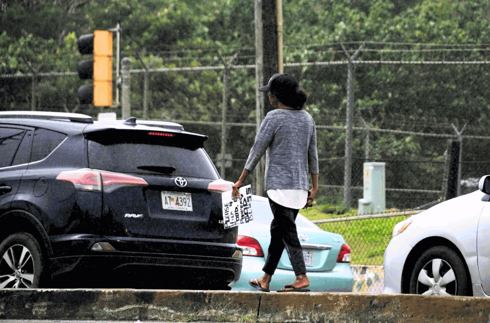 A person holding a sign walks along a Marine Corps Drive median near the Micronesia Mall in Dededo on March 1, 2023. 