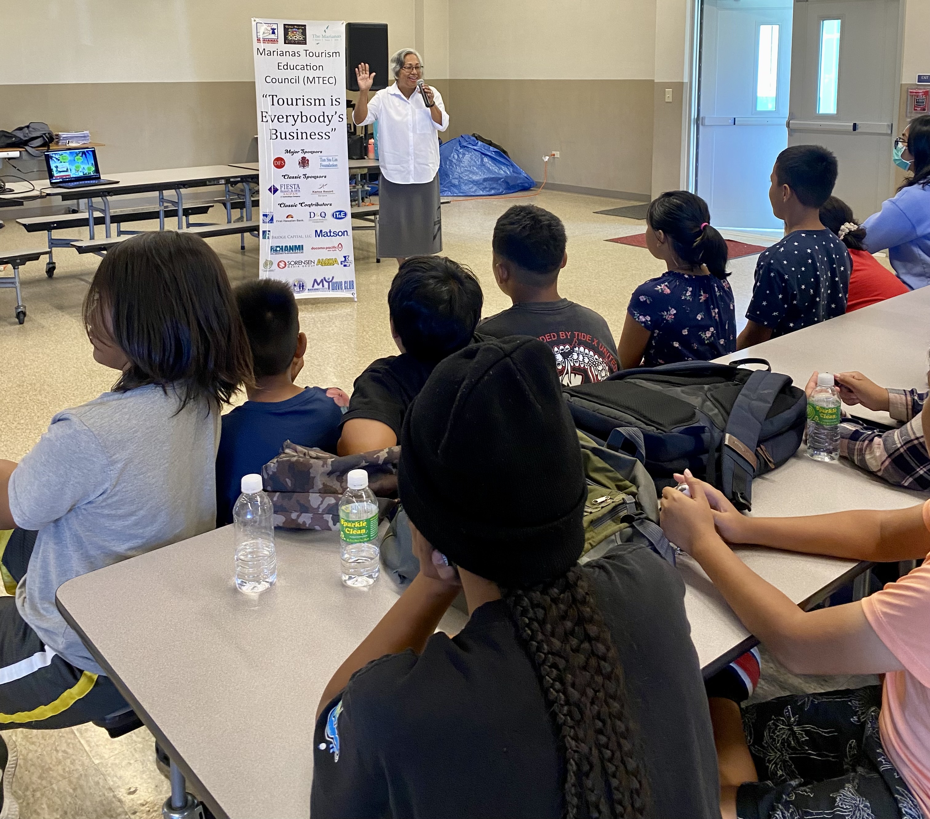Marianas Tourism Education Council Acting Chairwoman Vicky Benavente welcomes students of Koblerville Elementary to the educational outreach presentation of MTEC and the Marianas Visitors Authority on March 28, 2023, at the school.