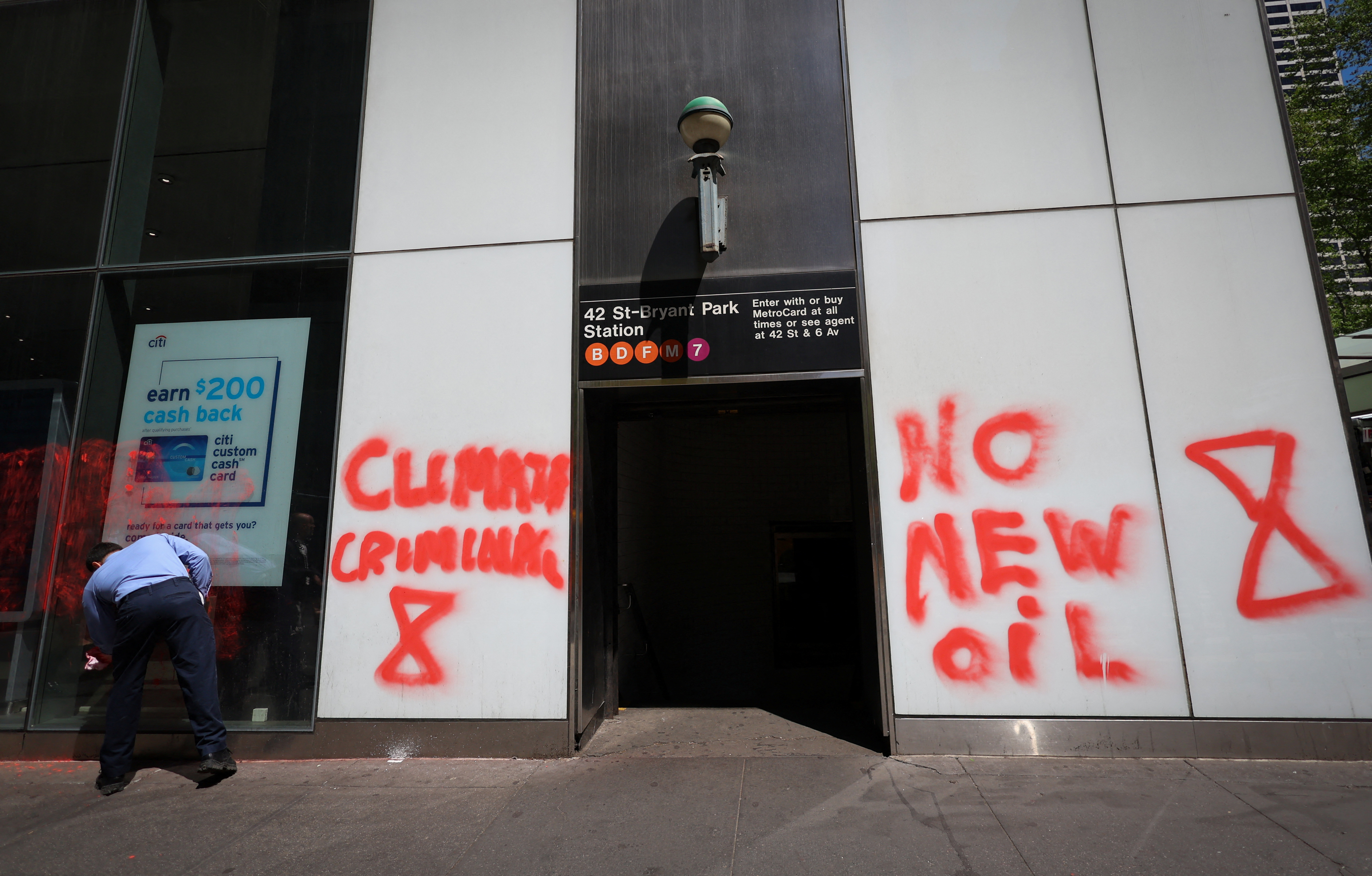 A worker cleans off a spray-painted message left by climate protestors on the outside of a Citibank branch in Midtown Manhattan in New York City, New York, U.S., April 24, 2023. REUTERS/Mike Segar