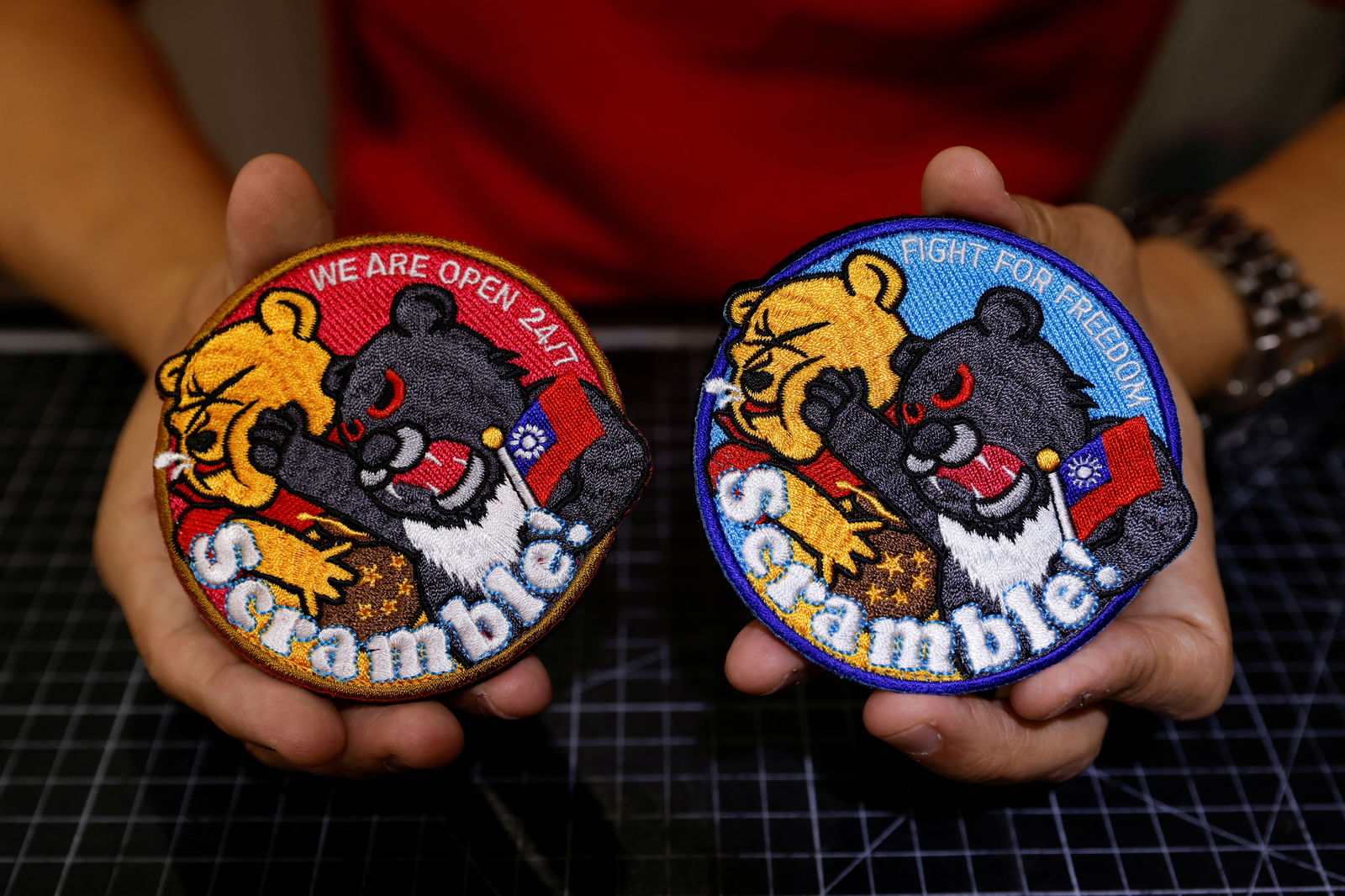 Alec Hsu shows to the camera patches depicting a Formosan black bear holding Taiwan’s flag and punching Winnie the Pooh at his store in Taoyuan, Taiwan, April 10, 2023. 