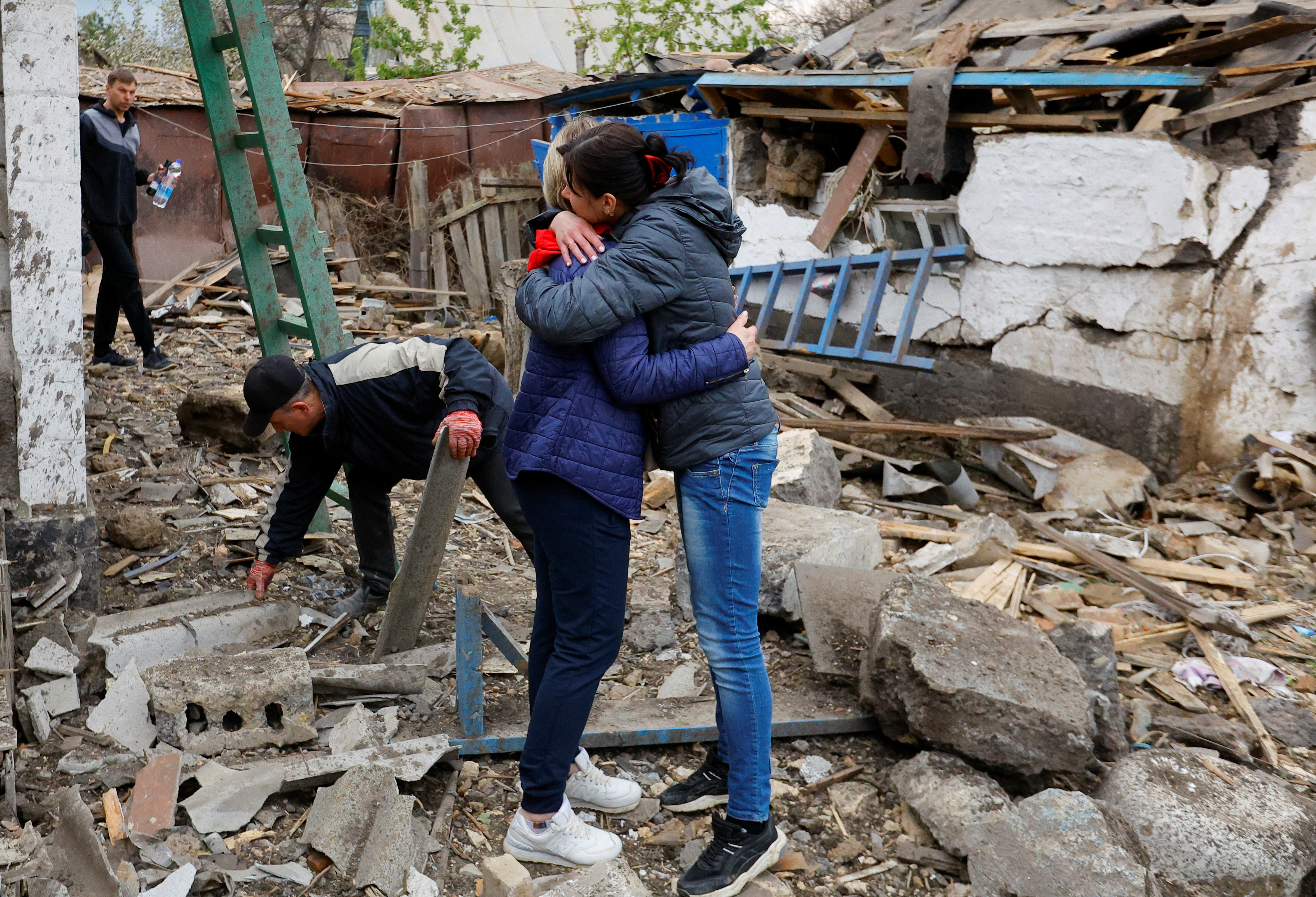 Local resident Irina Vovk, 38, embraces her neighbour while meeting outside their houses destroyed by shelling in the course of Russia-Ukraine conflict in Donetsk, Russian-controlled Ukraine, April 29, 2023. REUTERS/Alexander Ermochenko