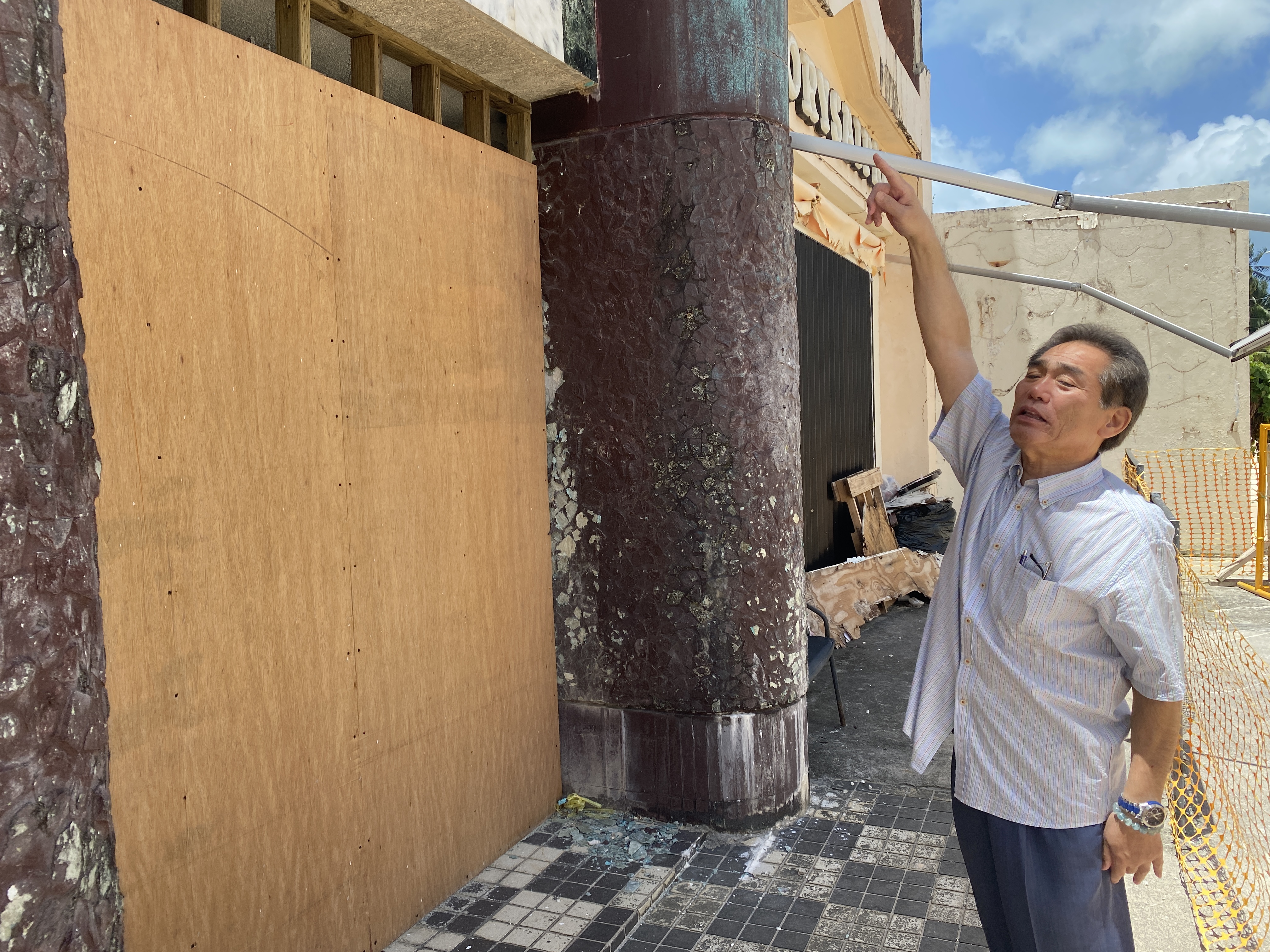 Hideaki Sawada stands in front of the barricade he erected to keep would-be burglars away from his office. He is pointing to where his office is located.