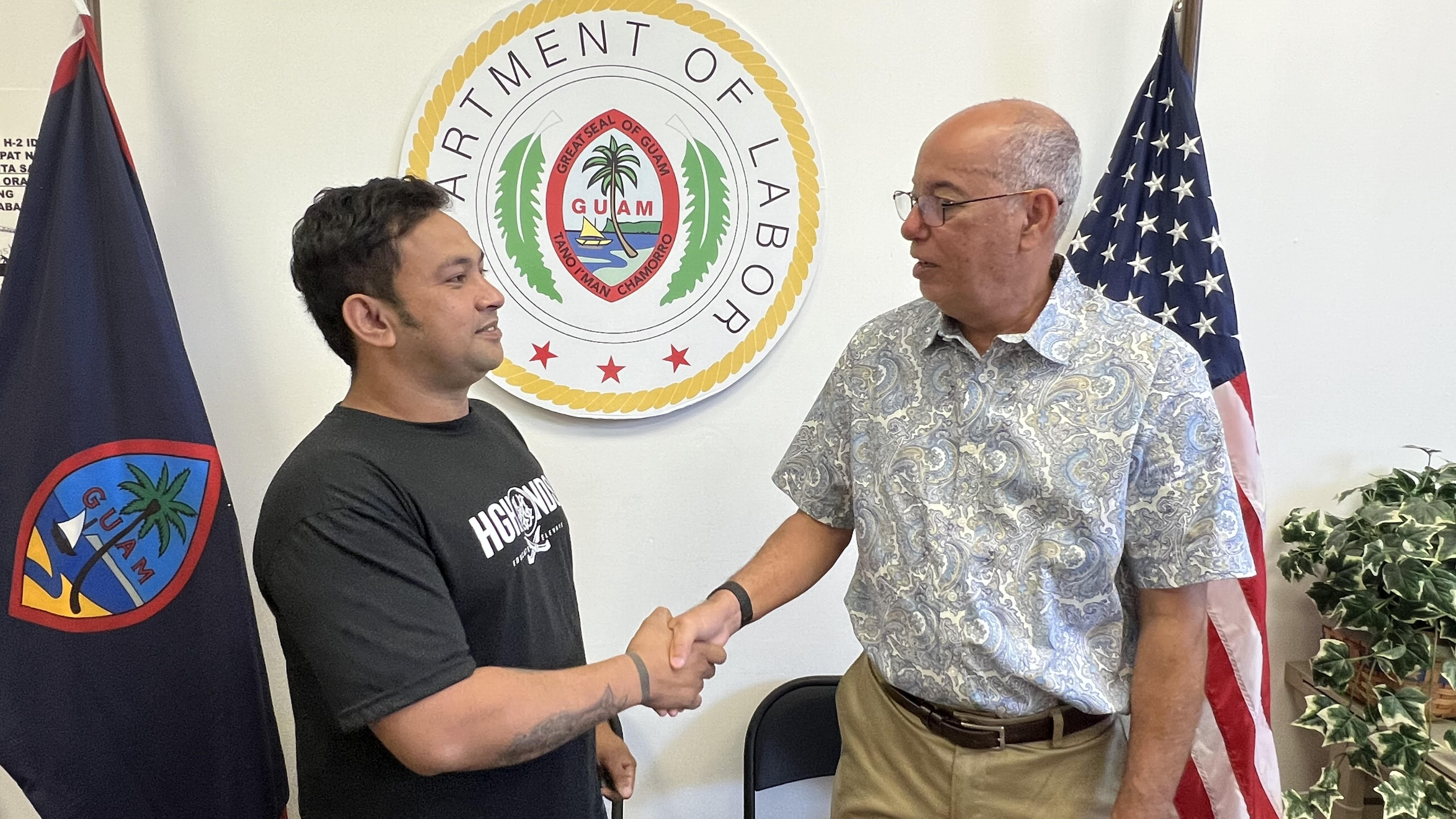 Ronel Tramado, left, an H-2B worker from the Philippines, shakes hands with Guam Labor Director David Dell'Isola.