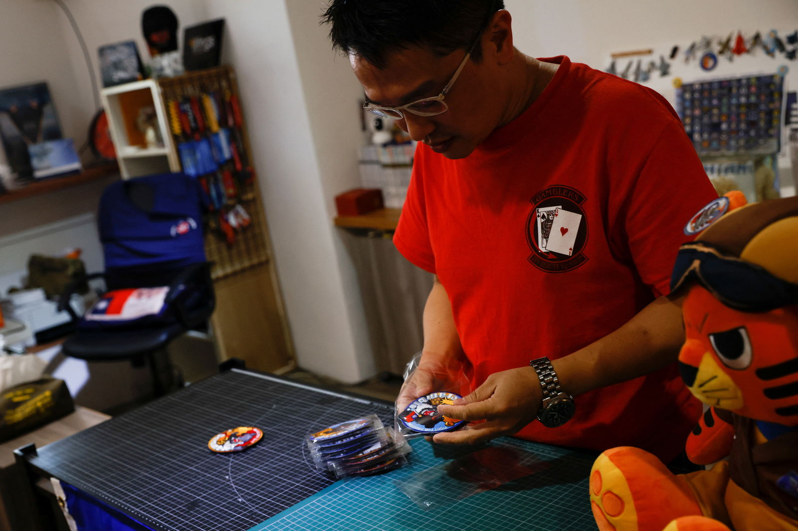 Alec Hsu puts patches depicting a Formosan black bear holding Taiwan’s flag and punching Winnie the Pooh, inside individual plastic bags at his store in Taoyuan, Taiwan, April 10, 2023.