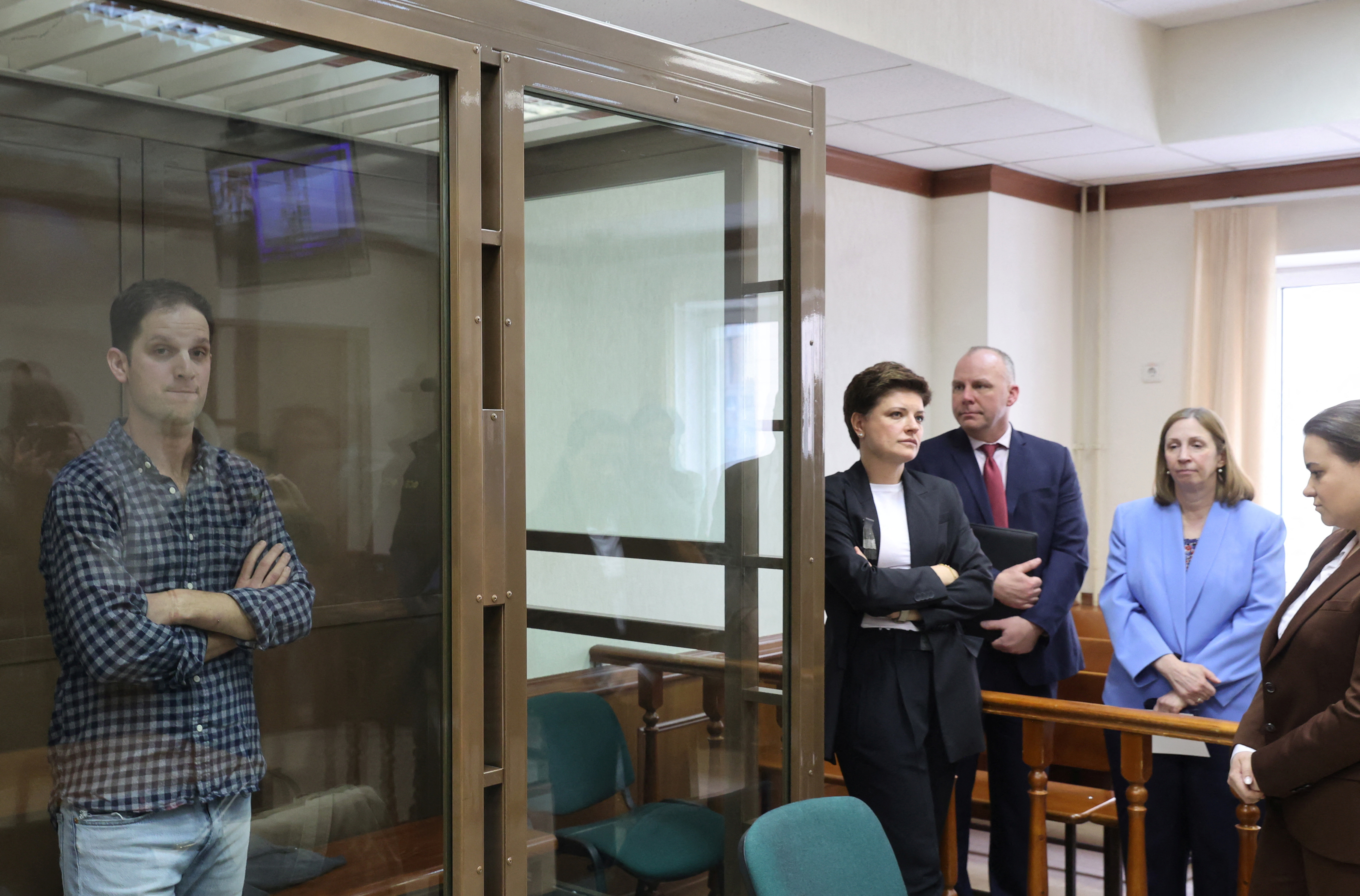 Wall Street Journal reporter Evan Gershkovich, who was detained in March while on a reporting trip and charged with espionage, stands behind a glass wall of an enclosure for defendants, while U.S. Ambassador to Russia Lynne Tracy and lawyers Tatyana Nozhkina and Maria Korchagina appear in a courtroom before a hearing to consider an appeal against Gershkovich's detention, in Moscow, Russia April 18, 2023. REUTERS/Yulia Morozova